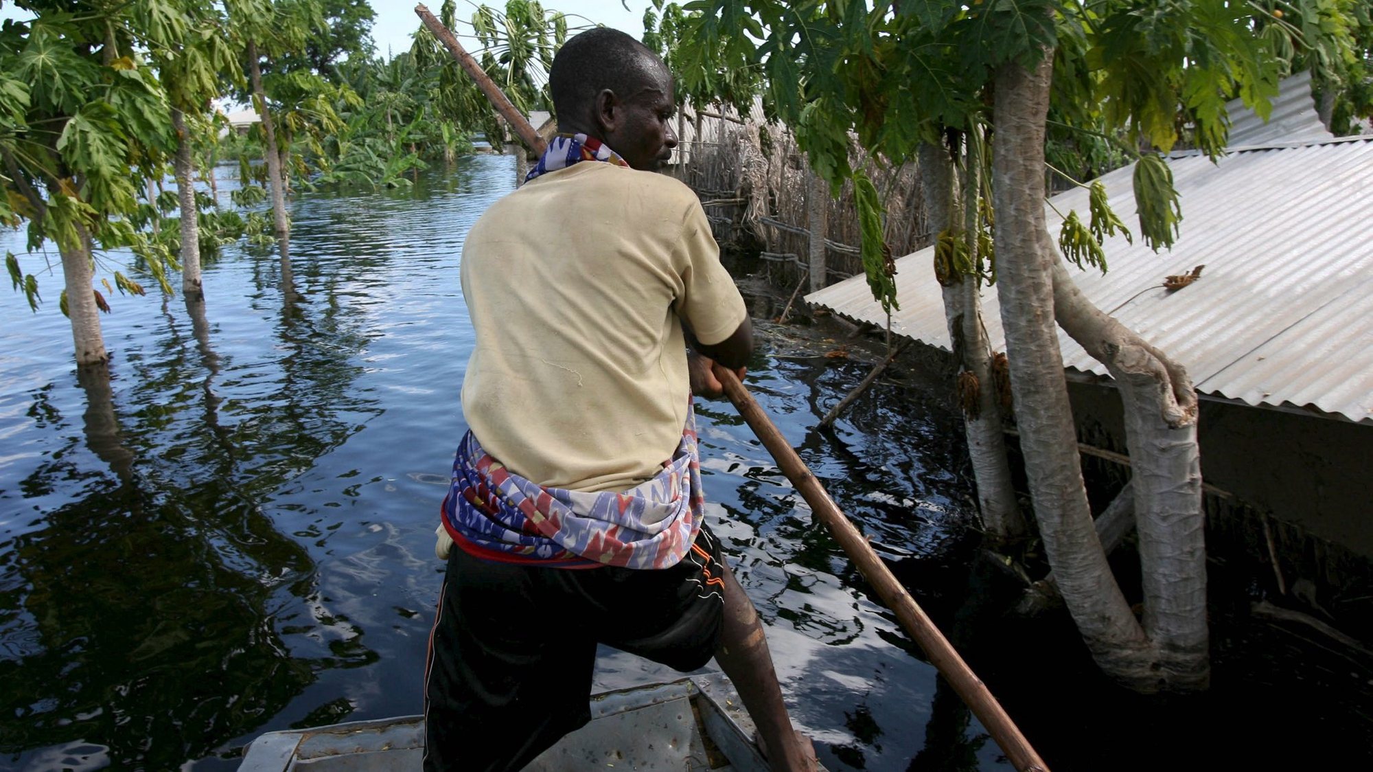 epa00879100 A villager steers his boat through a flooded village along the Juba river in southern Somalia near the village of Jamame on Wednesday, 06 December 2006. After years of drought Somalia is suffering from the worst flooding in over 50 years leaving an estimated 120 killed and tens of thousands homeless.  EPA/STEPHEN MORRISON