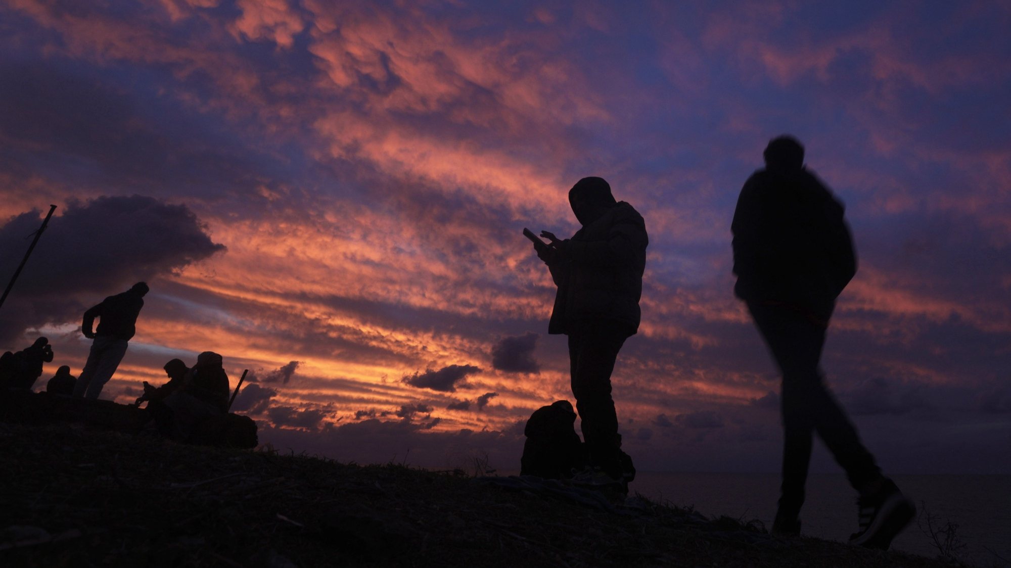 epa11034927 Palestinians check the internet reception on their mobiles phones during sunset in the west of central Gaza strip on 17 December 2023. More than 18,000 Palestinians and at least 1,200 Israelis have been killed, according to the Palestinian Health Ministry and the Israel Defense Forces (IDF), since Hamas militants launched an attack against Israel from the Gaza Strip on 07 October, and the Israeli operations in Gaza and the West Bank which followed it.  EPA/MOHAMMED SABER