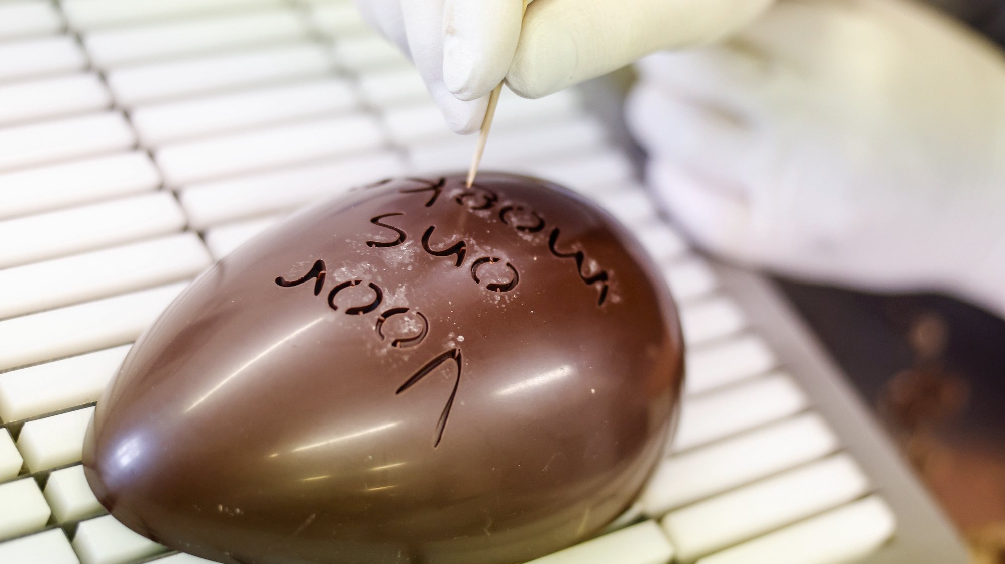 epa11247017 An employee works on an Easter egg at the chocolate factory &#039;Confiserie Felicitas&#039; in Hornow near Spremberg, Germany, 27 March 2024. The Confiserie Felicitas is a family company run by a Belgian couple who settled in Germany in the early 1990s with the idea to produce good chocolate based on a Belgian recipe. The weeks before Easter are the most important time of the year for the chocolates industry.  EPA/HANNIBAL HANSCHKE