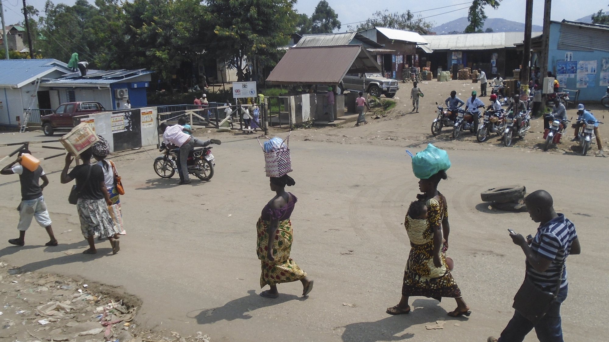 epa07648542 Women carry bags on their heads as they walk the street of Mpondwe, where the Uganda Red Cross set up a check point to screen people crossing borders into Uganda from Democratic Republic of the Congo, in the border town of Mpondwe in western Uganda, 14 June 2019. World Health Organization (WHO) is considering declaring Ebola an &#039;international emergency&#039; after two died in Uganda as the virus is spread from DR Congo to Uganda.  EPA/ENID NINSIIMA