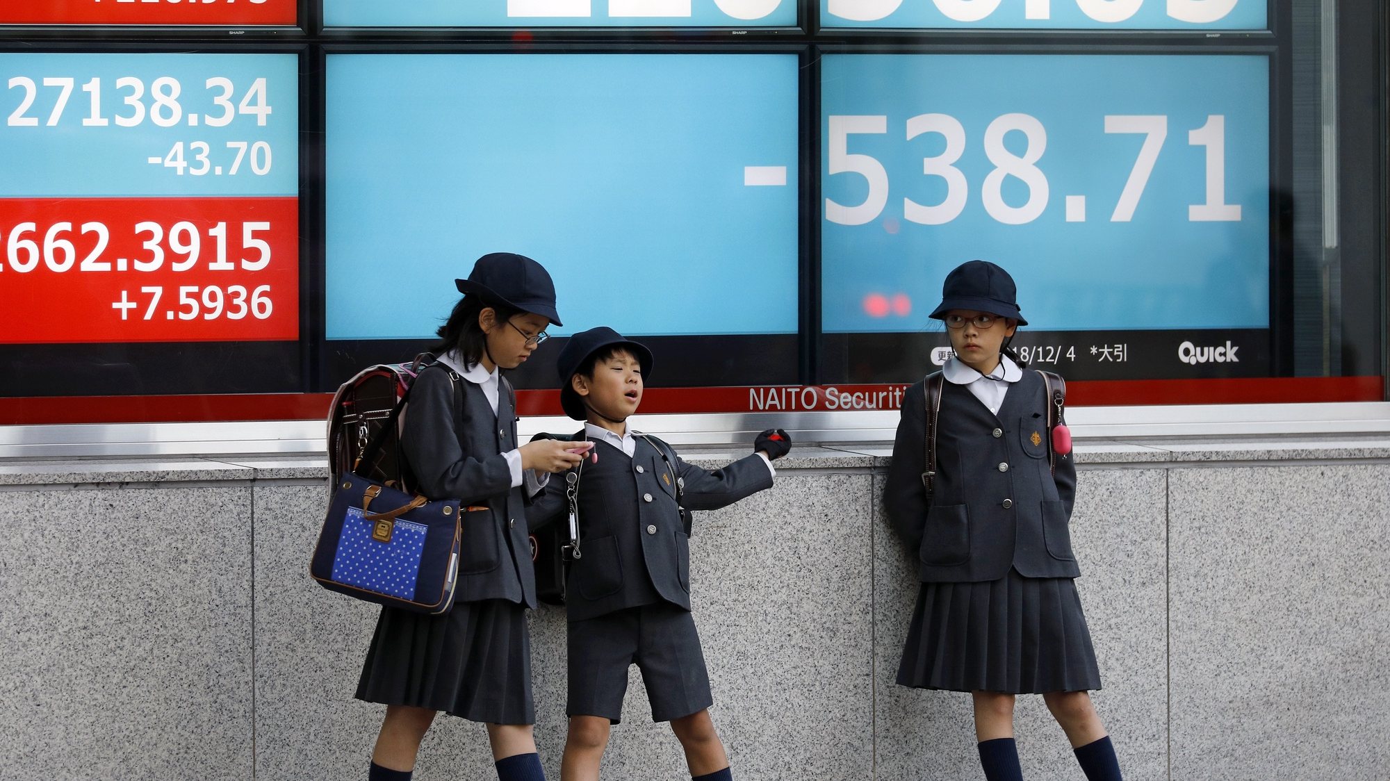 epa07207500 School children stand before a stock market indicator board in Tokyo, Japan, 04 December 2018. Tokyo stocks fell sharply following a stronger yen against the USD and profit-taking. The Nikkei 225 index dropped 538.71 points, or 2.39 percent, to to close at 22,036.05.  EPA/FRANCK ROBICHON