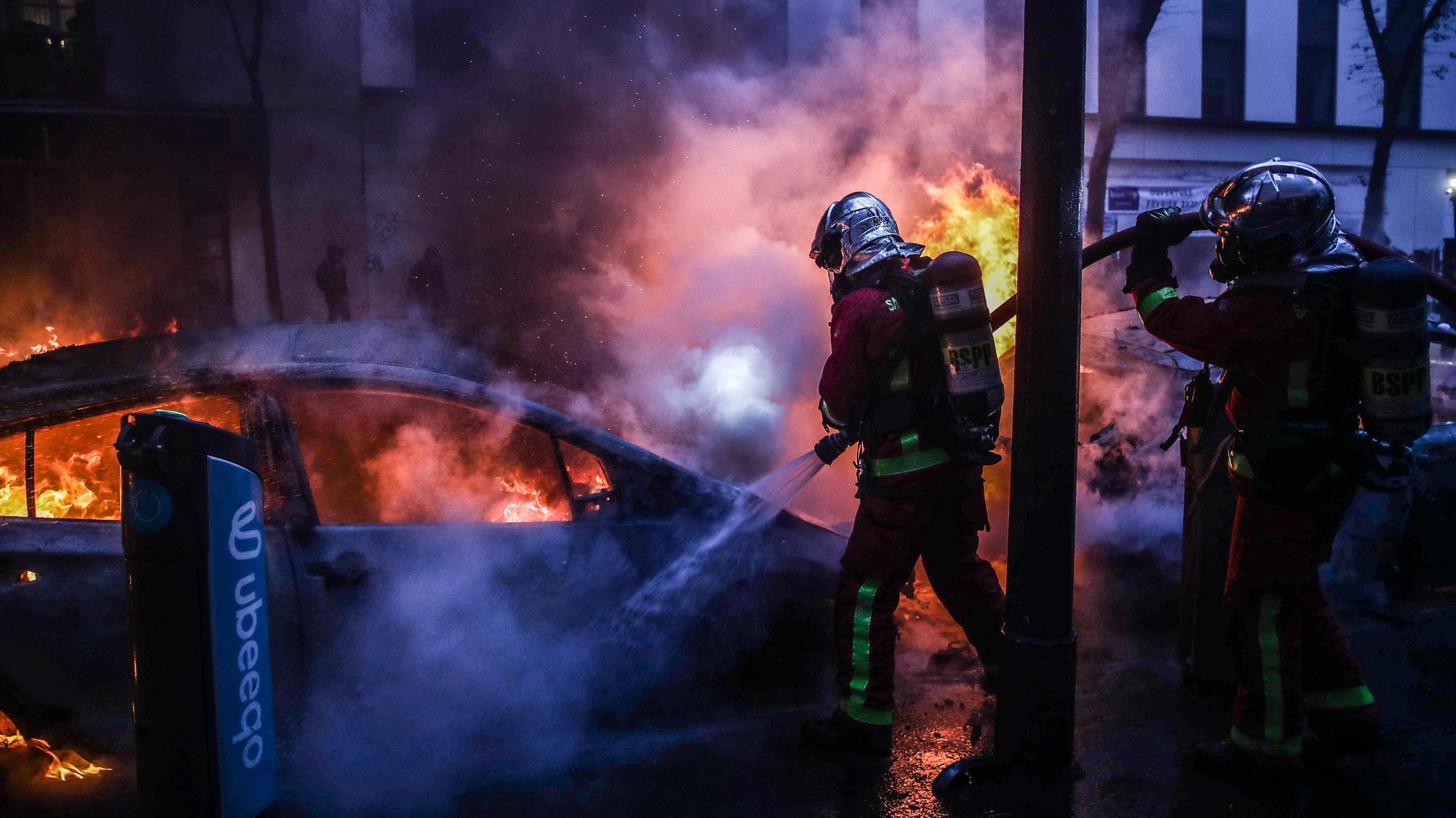 epa08865021 Firefighters extinguish a fire as several cars burn during a protest against France&#039;s controversial global security law, during a protest in a street between Porte des Lilas and Gambetta square, in Paris, France, 05 December 2020. The global security legislation passed by the French Parliament aims to ban the distribution of photos in which police officers and gendarmes can be identified in a way which is harmful to their image  EPA/Mohammed Badra