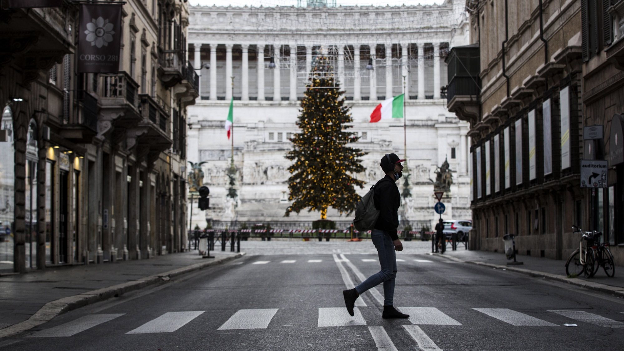 epaselect epa08903754 A man crosses a street backdropped by the Christmas tree in Piazza Venezia and the Victor Emmanuel II National Monument during the Christmas lockdown in Rome, Italy, 25 December 2020. Italy is in lockdown over ten days including the Christmas holidays in lockdown after government restrictions aimed at stopping physical contact during the festive season came into force on 24 December.  EPA/ANGELO CARCONI