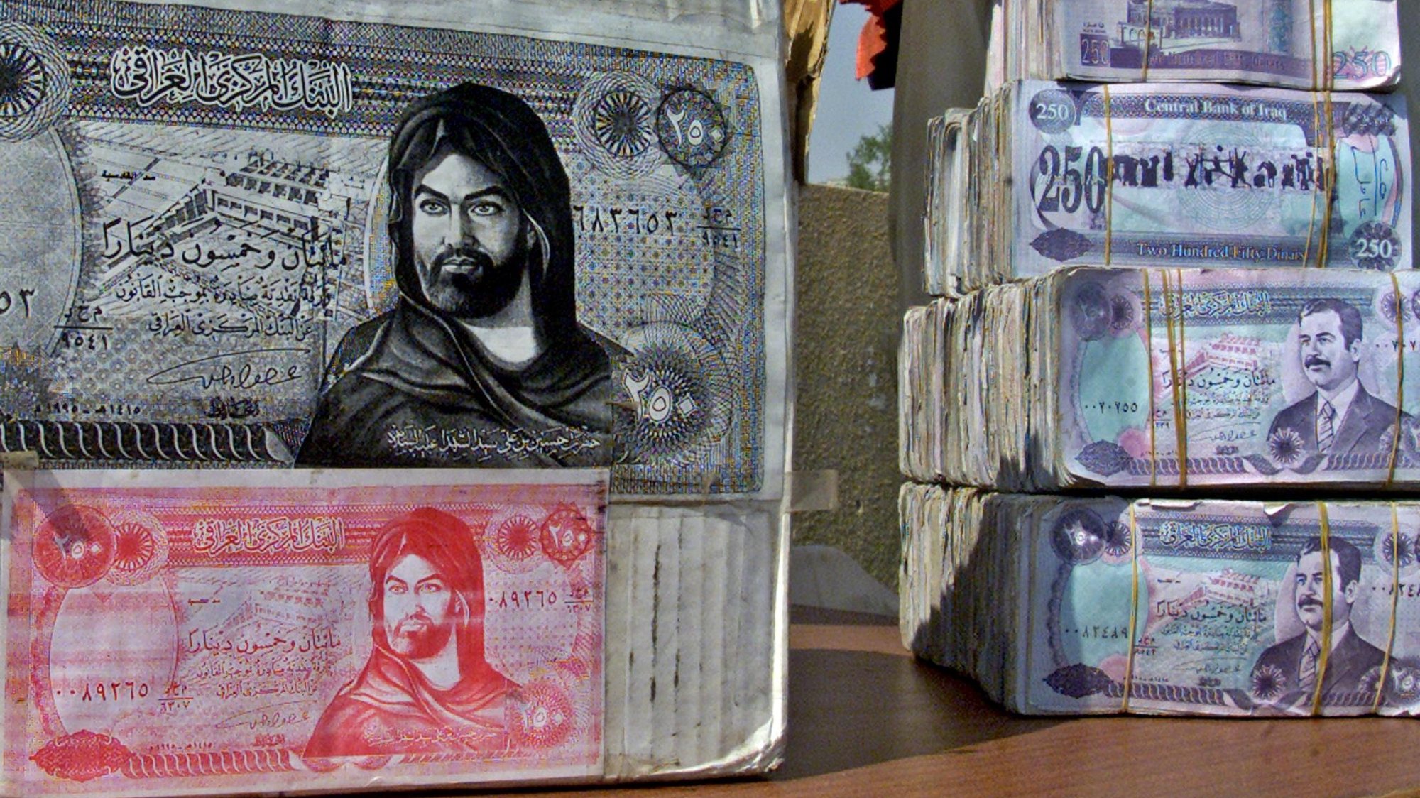 Iraqi Dinar banknotes showing toppled leader Saddam Hussein and counterfeit money (L) showing Imam Hussein, the martyred grandson of Islam&#039;s Prophet Mohammed, are seen on a stall in Fardous Square or &quot;Paradise Square&quot; in Baghdad 27 June 2003. The money-changer, who is a Shiite Muslim, explained that when the coalition forces leave, the people of Iraq, 80% of who are Shiites, would like their currency to look like this. AFP PHOTO/Sabah ARAR