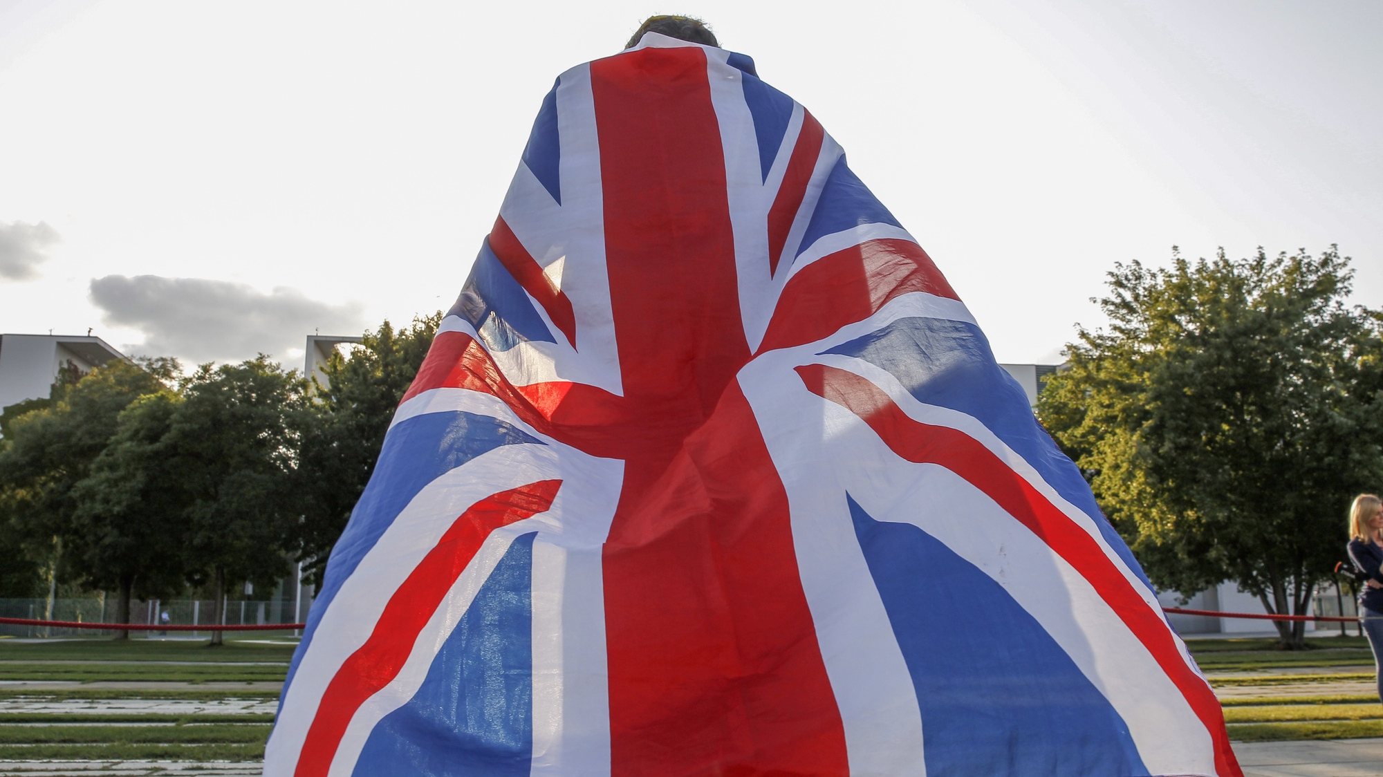 epa07784683 A visitor wrapped in a British flag stands in front of the Chancellery duringt the visit of British Prime Minister Boris Johnson in Berlin, Germany, 21 August 2019. Prior to the G7 summit in Biarritz form 24 to 27 August 2019, Johnson meets Angela Merkel and on the next day French President Emmanuel Macron. In the talks, Johnson is expected to try to resume the Brexit talks, so that it will not come to a &#039;no deal&#039; exit of the United Kingdom from the EU on 31 October 2019.  EPA/MICHELE TANTUSSI