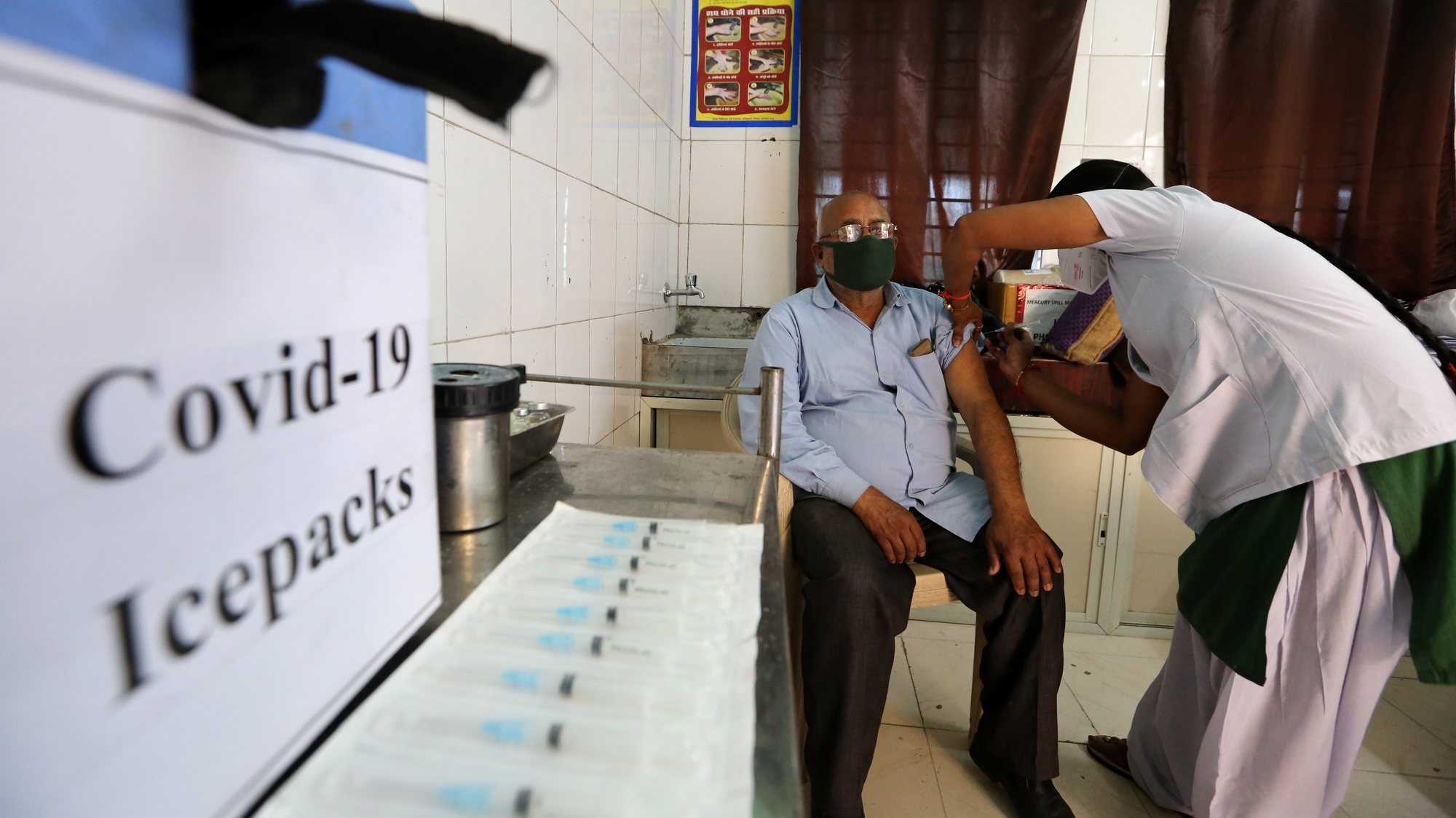 epa09075621 A man receives a shot of COVID-19 vaccine during the vaccination drive at a clinic in Misrod village, Bhopal, India, 15 March 2021. Phase two of the COVID-19 vaccination started in India on 01 March for people aged 60 and above.  EPA/SANJEEV GUPTA