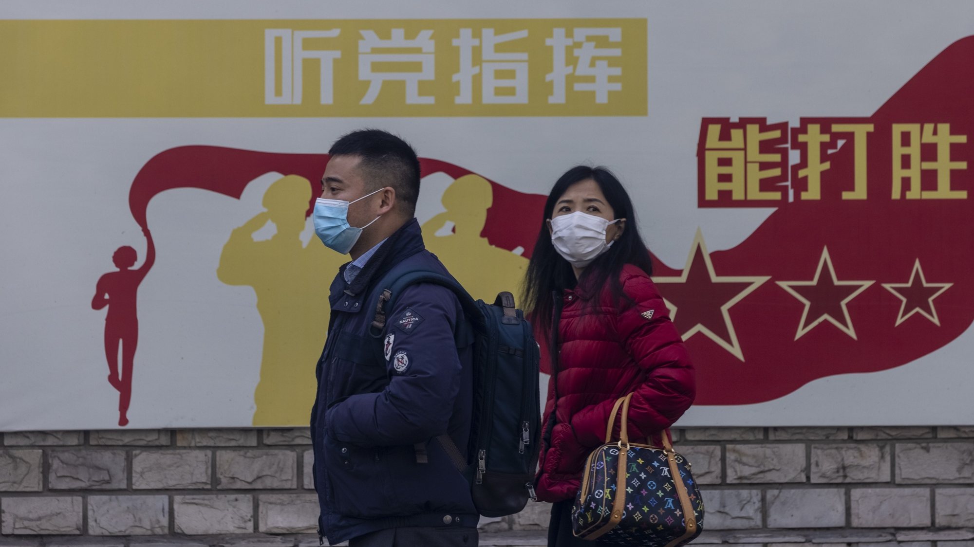 epa09064880 A couple passes by a propaganda poster on the street in Shanghai, China, 10 March 2021. One year after the World Health Organisation (WHO) declared the pandemic of the COVID-19 disease caused by the SARS-CoV-2 coronavirus, China managed to keep it at bay. At the same time, the United States plunged into a health crisis that has already left more than half a million people dead.  EPA/ALEX PLAVEVSKI