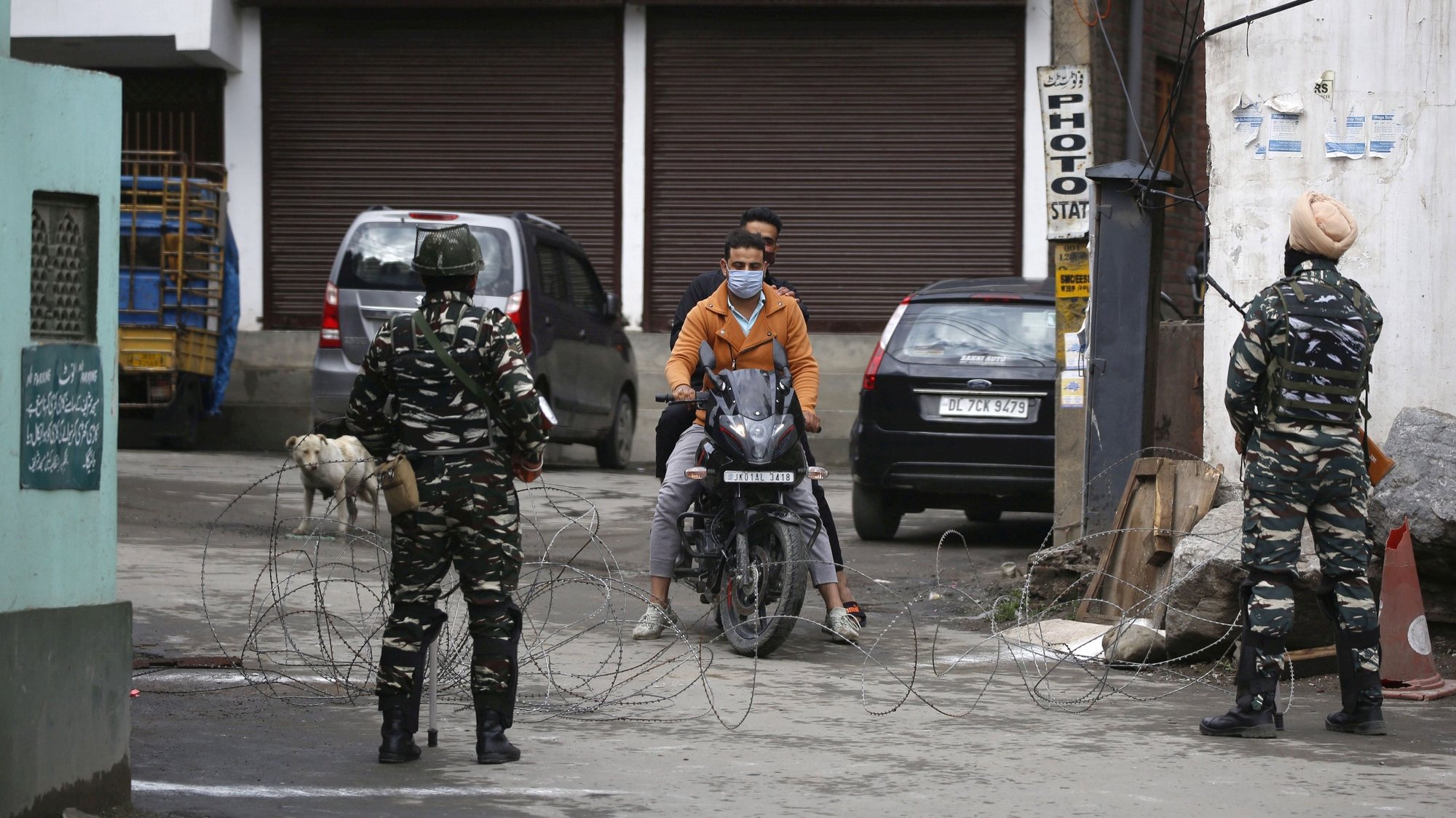 epa09195995 Indian paramilitary soldiers stop a Kashmiri motorcyclist near barbed wire set up as barricade during lockdown in Srinagar, the summer capital of Indian Kashmir, 13 May 2021. Kashmiri Muslims offer Eid prayers at heritage Aali Masjid and mosques in interior areas while following Covid guidelines. Most of major mosques and shrines in Indian Kashmir remained closed in view of Covid lockdown enforced by authorities to prevent spread of Coronavirus pandemic.  EPA/FAROOQ KHAN