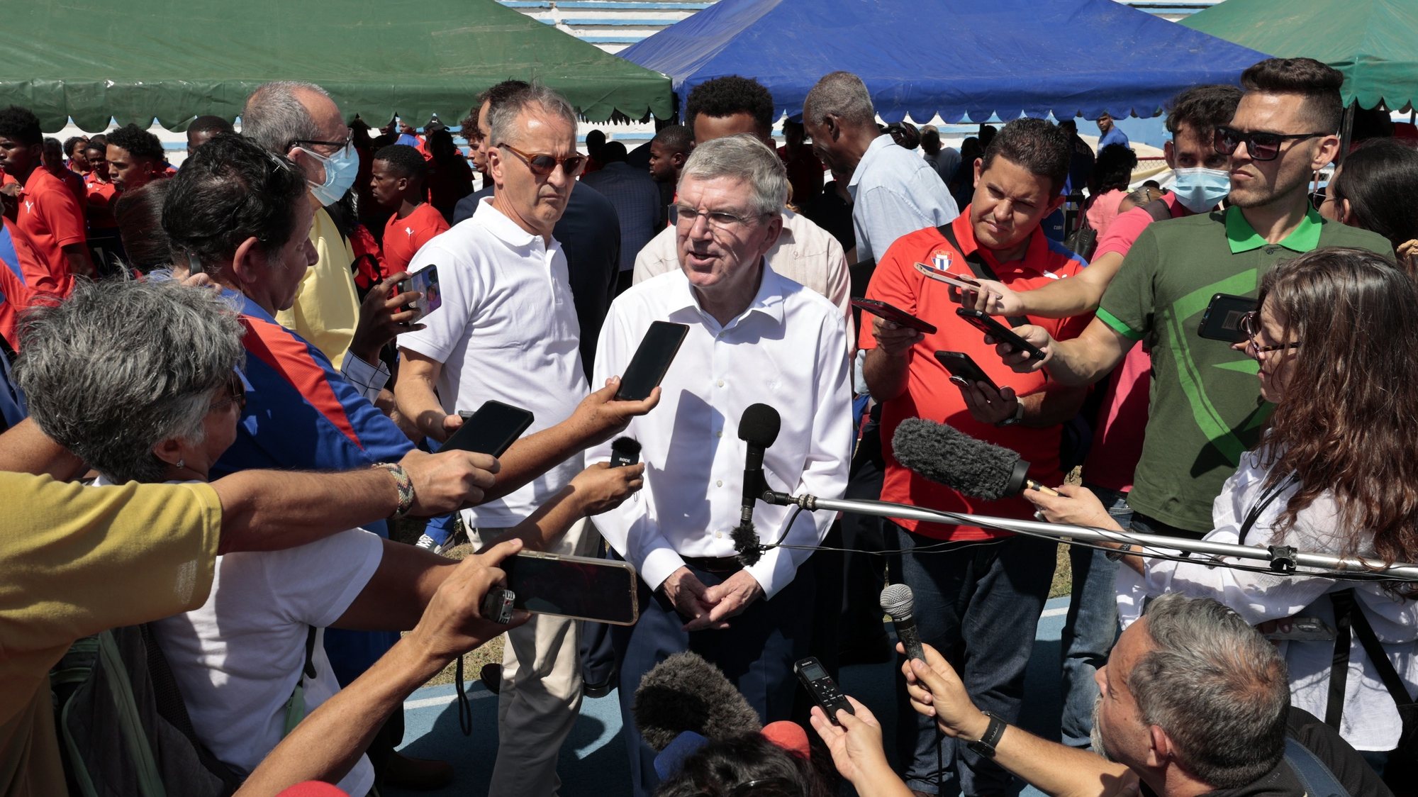 epa10501293 The president of the International Olympic Committee (IOC), the German Thomas Bach (C), speaks with journalists during a tour for the inauguration of an athletics track in Havana, Cuba, 03 March 2023. Bach is on a two-day visit to Cuba that started on 02 March.  EPA/Ernesto Mastrascusa