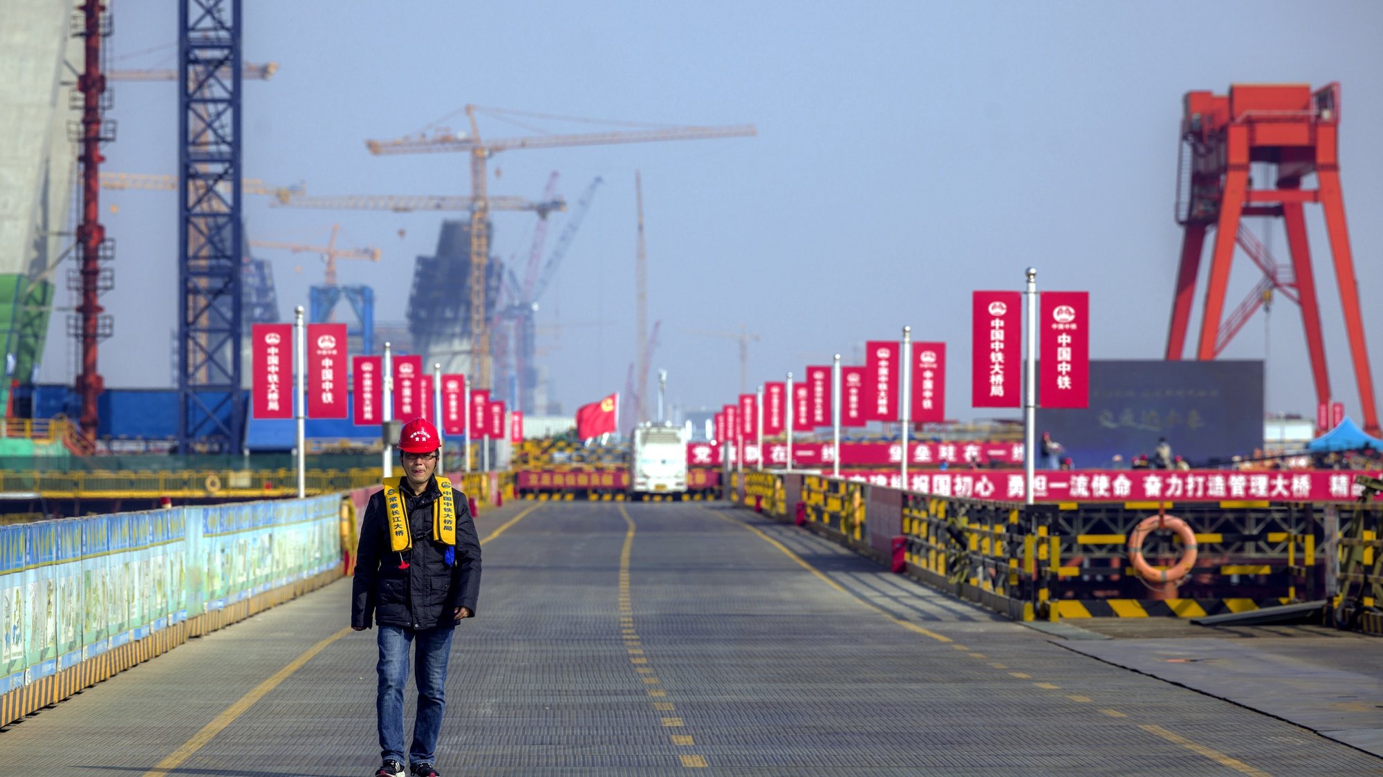 epa09629075 A man walks on a Changzhou-Taizhou Yangtze River Bridge pylon construction site, during the organised media tour in Changzhou, Jiangsu province, China, 08 December 2021. The Changzhou-Taizhou Yangtze River Bridge connects the two cities across the river. It is a three-in-one cross-river passage that integrates expressways, intercity railways, and first-class highways. Construction started in January 2019 and is expected to be completed in 2024. The main channel bridge adopts a double-layer 1176-meter cable-stayed bridge, and the dedicated channel bridge has a steel arch bridge with a main span of 388 meters.  EPA/ALEX PLAVEVSKI
