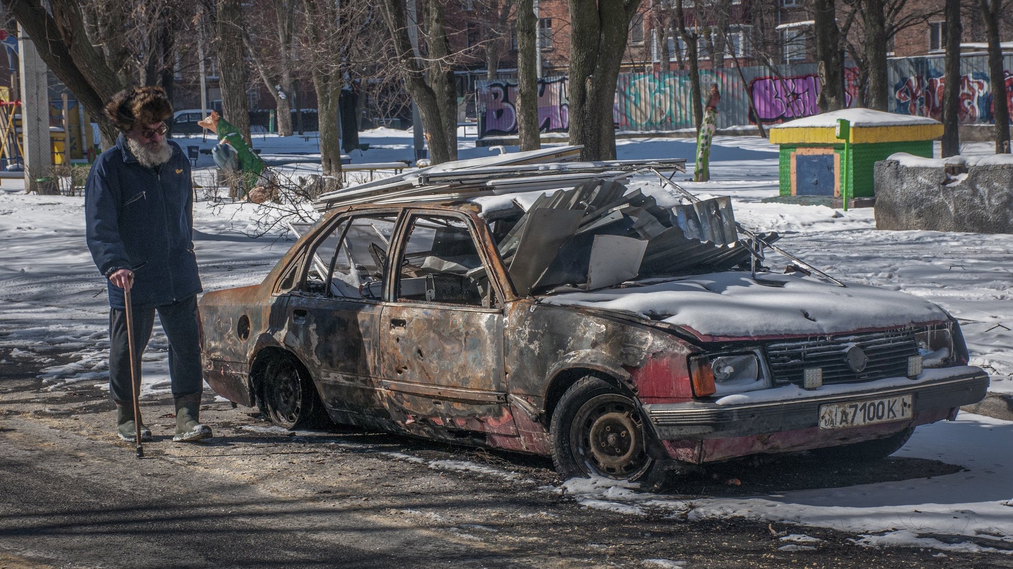 epa09819174 A man walks near a burned car in downtown of Kharkiv, Ukraine, 12 March 2022. Russian troops entered Ukraine on 24 February prompting the country&#039;s president to declare martial law and triggering a series of announcements by Western countries to impose severe economic sanctions on Russia.  EPA/VASILIY ZHLOBSKY