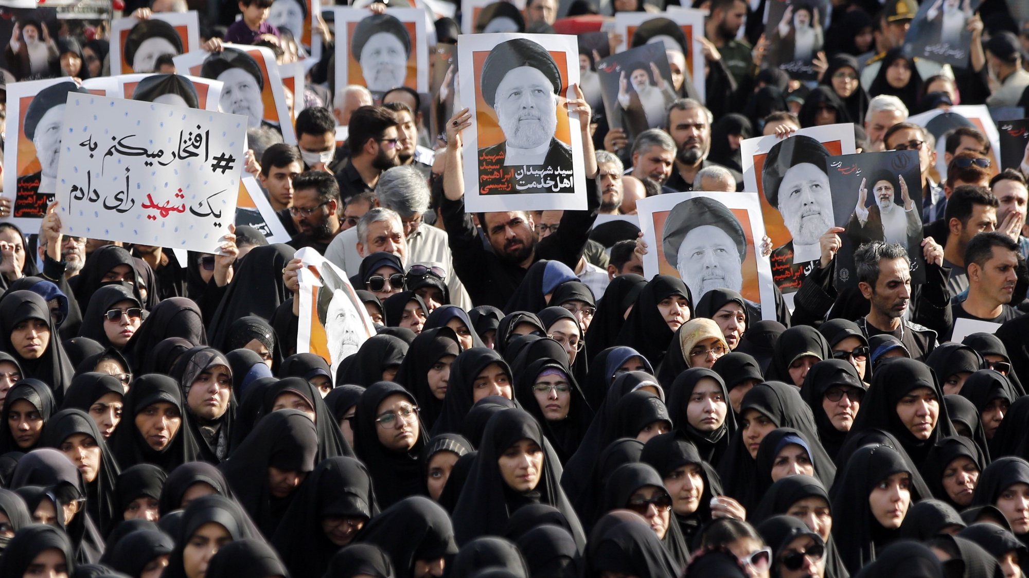 epaselect epa11355939 Iranians, among them women clad in black chadors, hold posters of late Iranian President Ebrahim Raisi as they take part in a mourning ceremony in Tehran, Iran, 20 May 2024. Iranian President Raisi, Foreign Minister Amir-Abdollahian and several others were killed in a helicopter crash on 19 May 2024, after an official visit in Iran&#039;s northwest near the border with Azerbaijan, the Iranian government confirmed. Iran announced a five-day public mourning.  EPA/ABEDIN TAHERKENAREH