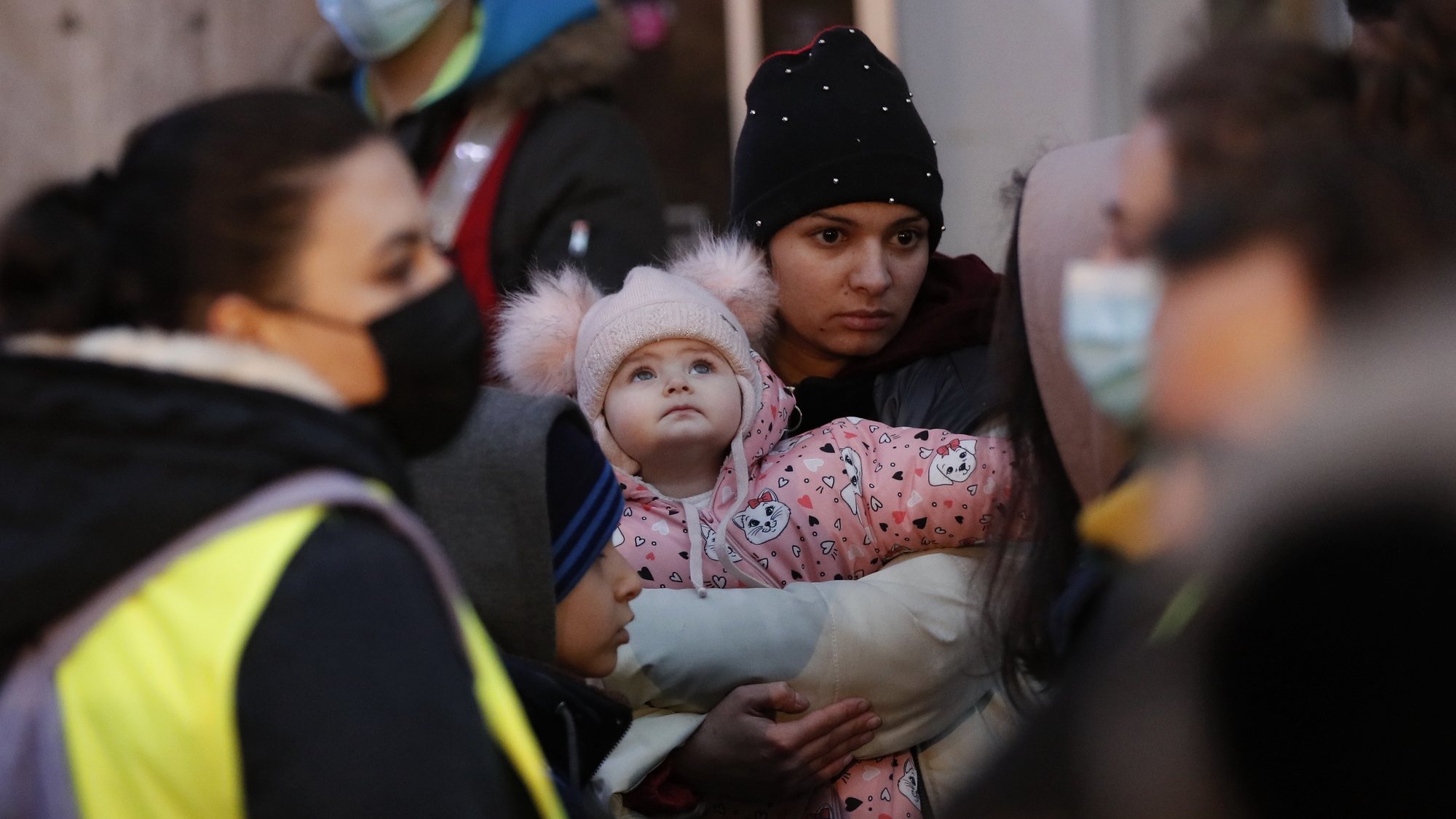 Uma mãe ucraniana e a sua filha ouvem as instruções dos voluntários antes de chegarem ao autocarro para apanharem o comboio para fugirem para a Roménia. 9 de março de 2022