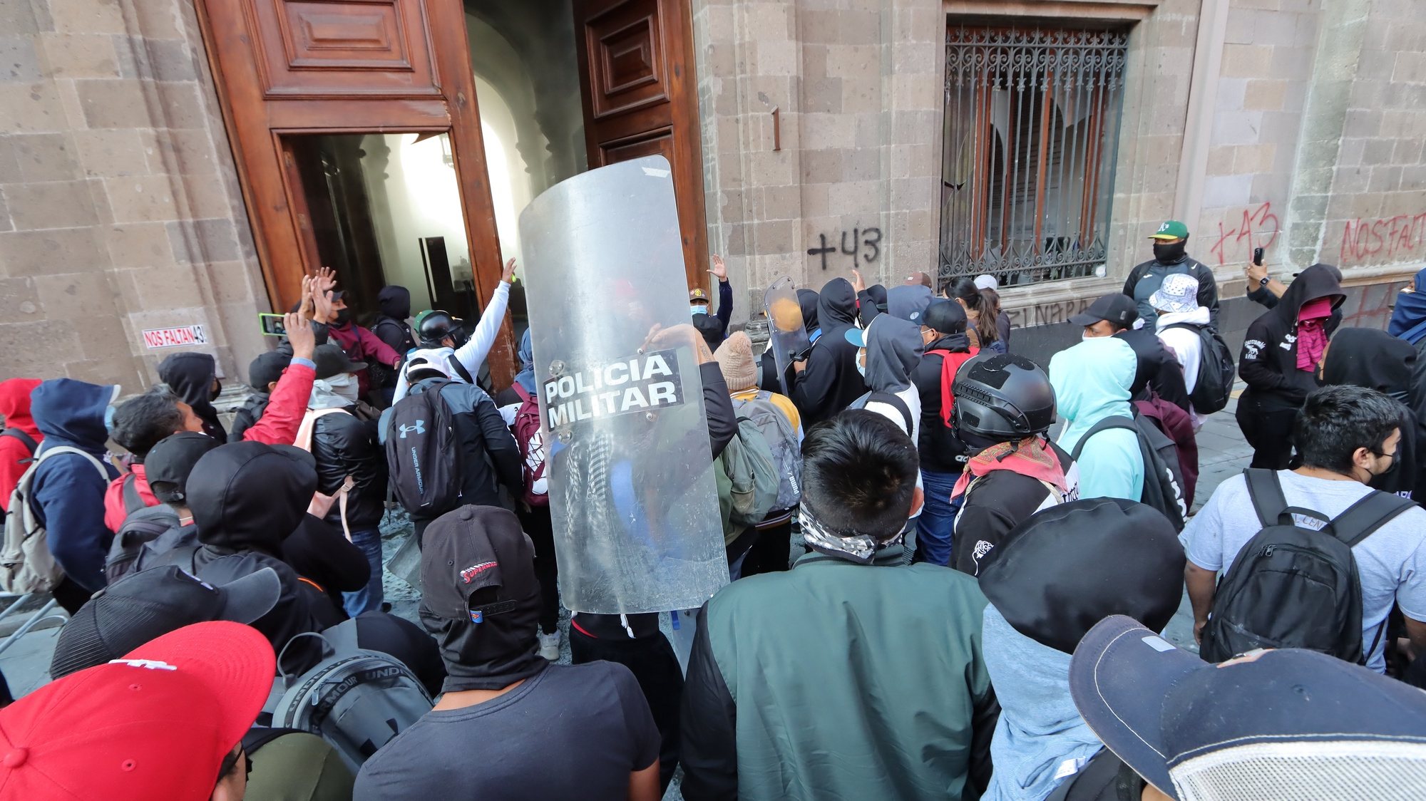 epa11202335 Hooded protesters vandalize one of the doors of the National Palace in Mexico City, Mexico, 06 March 2024. Mexicans protesting the disappearance of 43 Ayotzinapa students broke one of the main doors of the National Palace while President Andres Manuel Lopez Obrador held his morning press conference inside. The protesters, who accuse Lopez Obrador of not resolving the case to protect the military involved, took a van that belongs to the Federal Electricity Commission (CFE) to knock down Gate 1 on Moneda Street in the historic center of Mexico City.  EPA/Isaac Esquivel