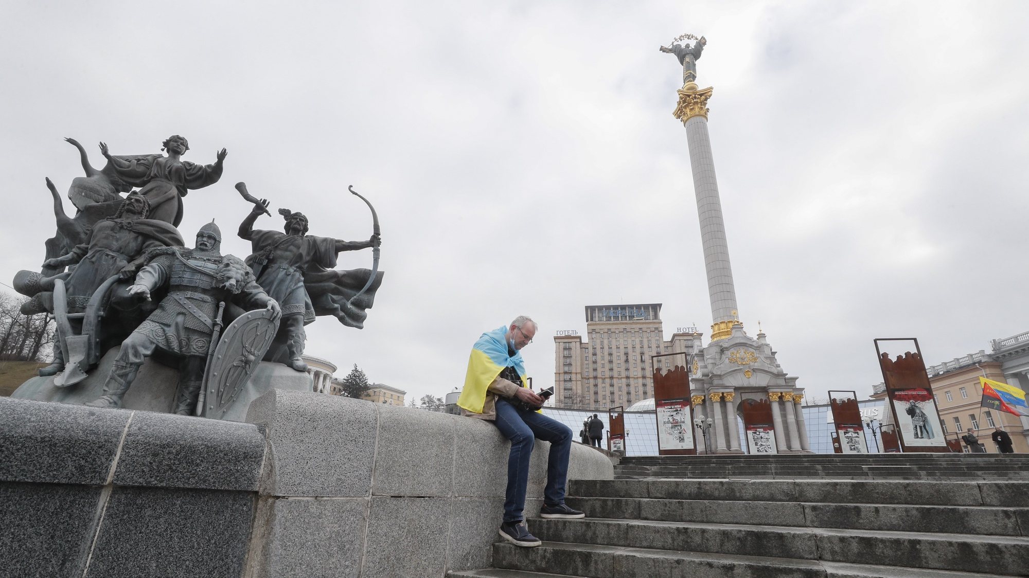 Um homem com a bandeira da Ucrânia nos ombros senta-se na Praça da Independência de Kiev, Ucrânia. 24 de fevereiro de 2022