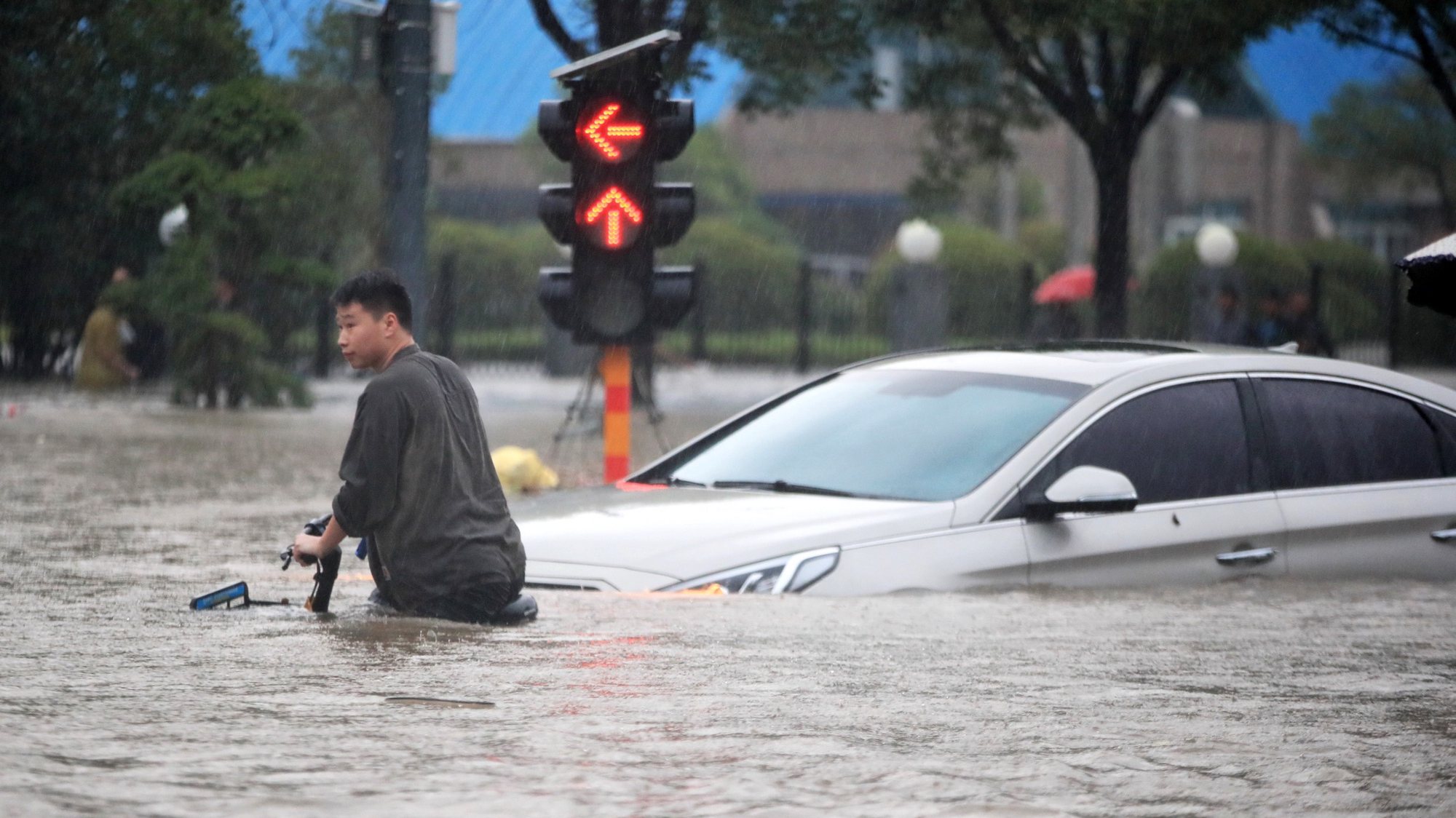 epa09356177 A man walks in the flooded road after record downpours in Zhengzhou city in central China&#039;s Henan province Tuesday, July 20, 2021 (issued 21 July 2021). Heavy floods in Central China killed 12 in Zhengzhou city due to the rainfall yesterday, 20 July 2021, according to official Chinese media. Over 144,660 people have been affected by heavy rains in Henan Province since July 16, and over 10,000 had to be relocated, the provincial flood control and drought relief headquarters said Tuesday.  EPA/FEATURECHINA CHINA OUT