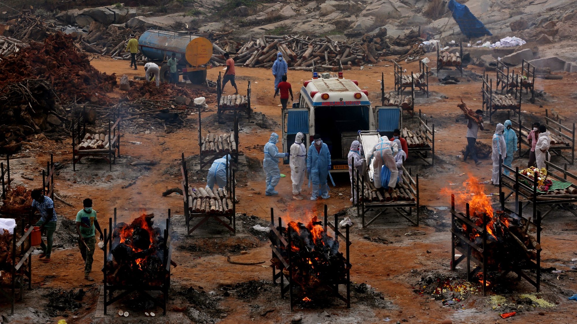 epa09175681 Funeral pyres for COVID-19 victims burn during a mass funeral at a makeshift cremation ground at Giddenahalli in the outskirts of Bangalore, India, 03 May 2021. India recorded a massive surge of 368,147 fresh Covid-19 cases and 3,455 deaths in the last 24 hours.  EPA/JAGADEESH NV
