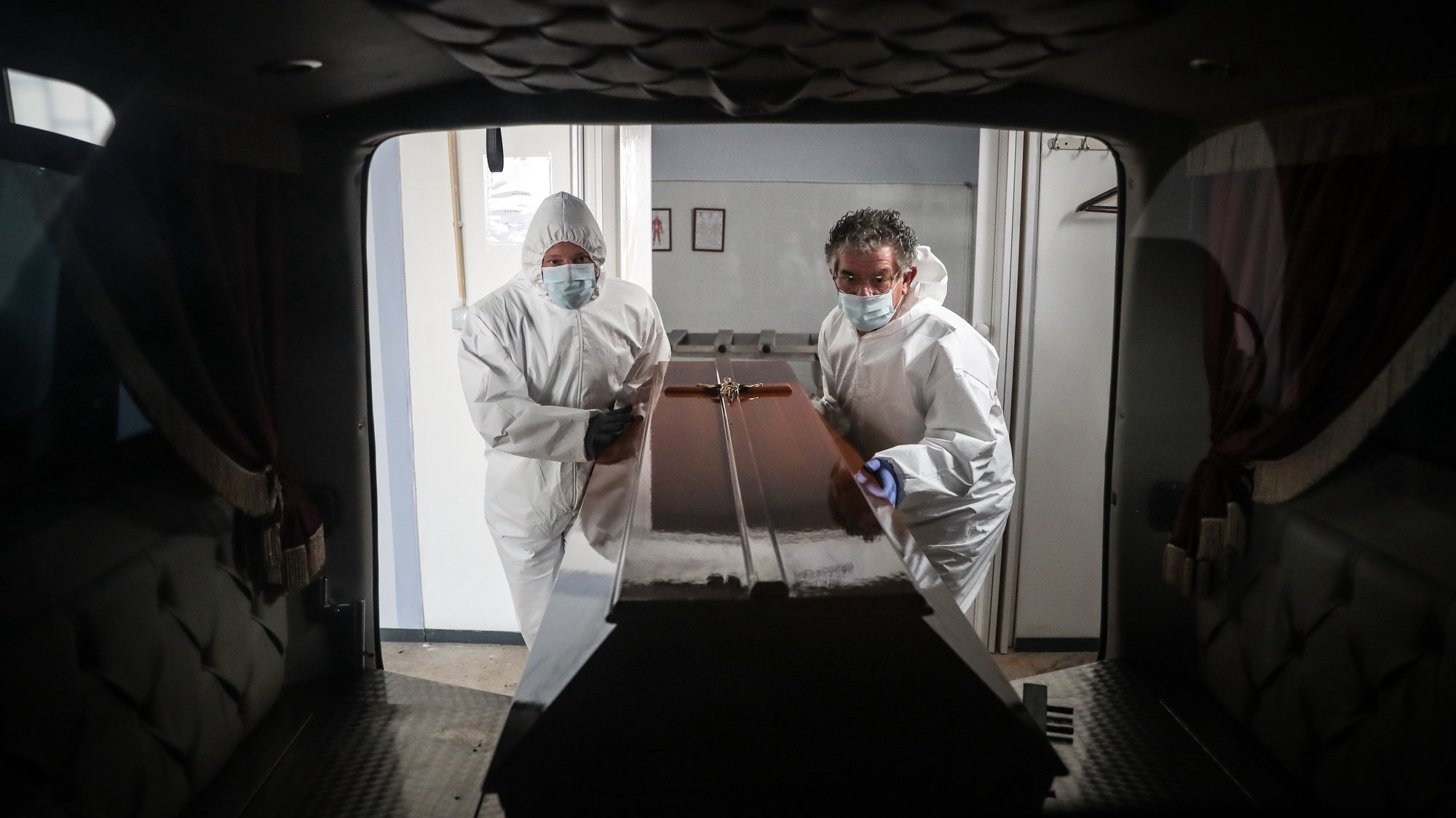 (11/23) Funcionários de uma agência funerária colocam um caixão de uma mulher que morreu vítima de covid-19 no interior de uma carrinha funerária, na Amadora, 30 de janeiro de 2021. Esta semana Portugal ultrapassou as 300 mortes diárias por covid-19, um novo máximo desde o início da pandemia. (ACOMPANHA TEXTO DA LUSA DO DIA 30 DE JANEIRO DE 2021). MÁRIO CRUZ/LUSA