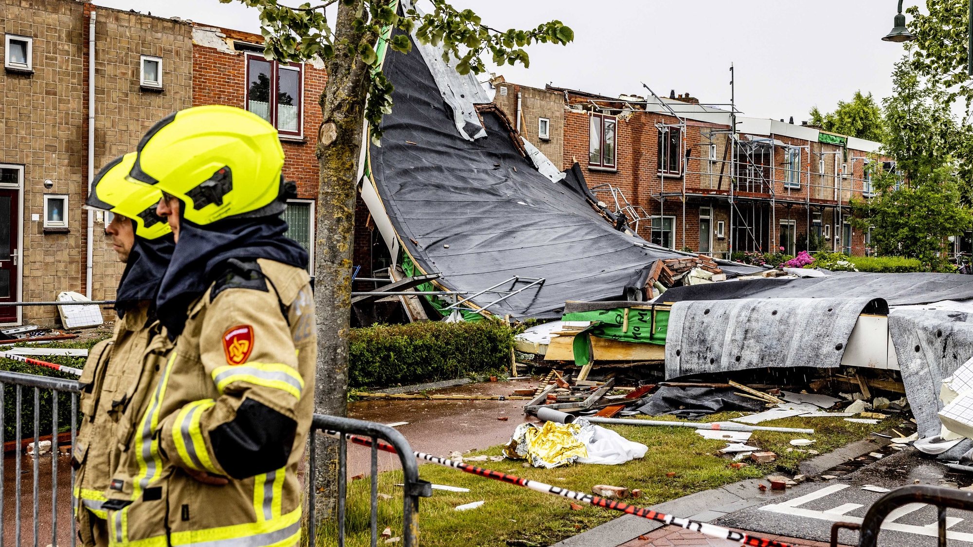 epa10036815 Emergency services personnel stand near a building damaged by a tornado in Zierikzee, Netherlands, 27 June 2022. According to Zeeland province authorities, one person was killed and ten others injured after a tornado hit Zierikzee on 27 June. The tornado also caused material damage to roof tiles of several buildings and trees in the area affected.  EPA/JEFFREY GROENEWEG