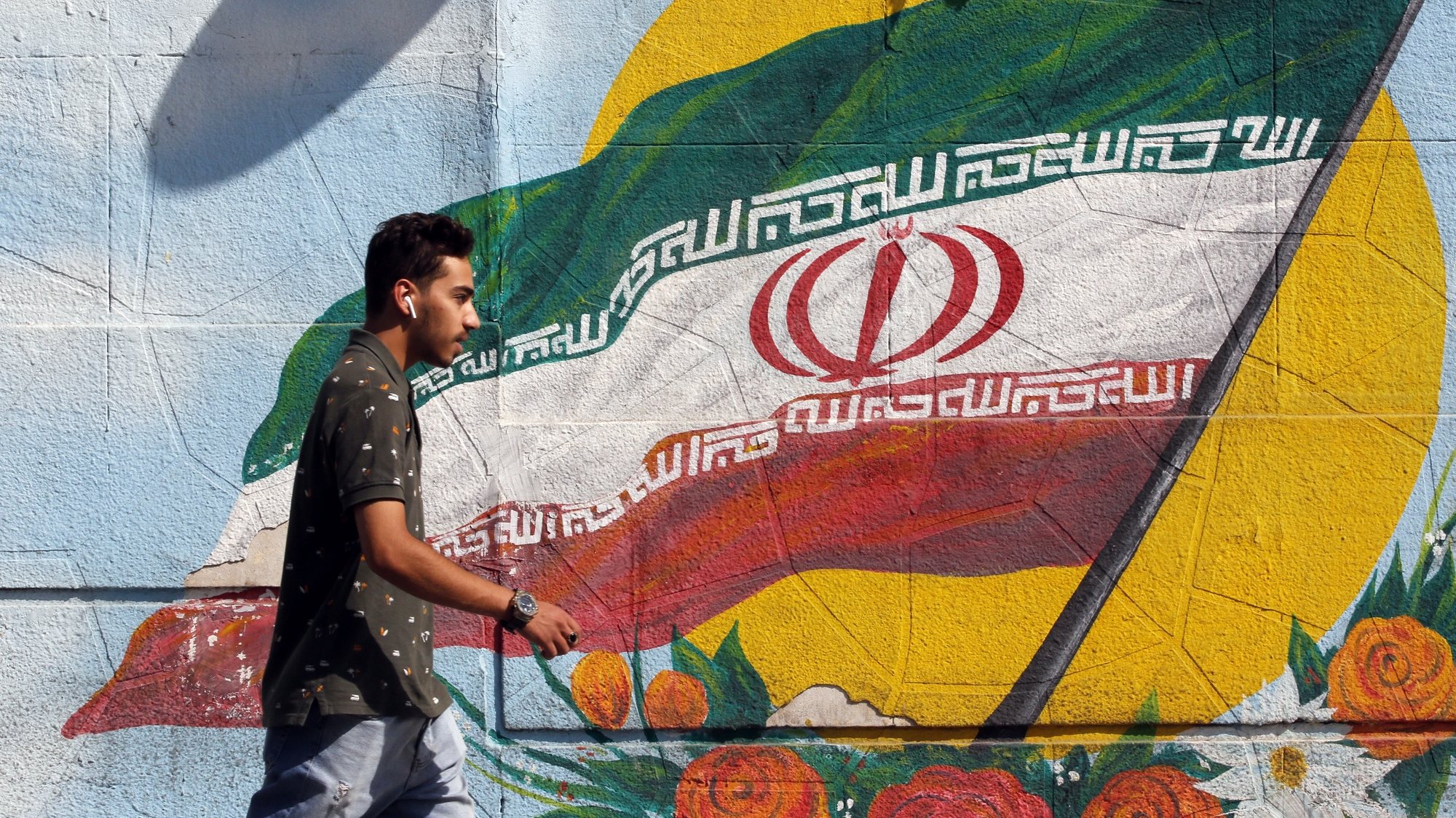 epa10209333 An Iranian boy walks next to a wall painting of Iran&#039;s national flag in a street, in Tehran, Iran, 27 September 2022. Iran has been facing many anti-government protests following death of Masha Amini, a 22 year old girl, who was detained on 13 September by the police unit responsible for enforcing Iran&#039;s strict dress code for women. Amini was declared dead on 16 September, after she spent 3 days in a coma. Protests first broke out in Saqez, hometown of Amini, during her funeral on 17 September.  EPA/ABEDIN TAHERKENAREH
