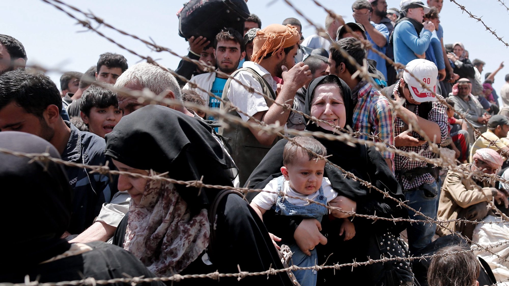 epa04791762 A picture taken from the Turkish side of the border between Turkey and Syria shows Syrian refugees waiting on the Syrian side of the border crossing near Akcakale, Sanliurfa province, south-eastern Turkey, 10 June 2015. More than 320,000 people are likely to have been killed in Syria&#039;s civil war, the Britain-based Syrian Observatory for Human Rights monitoring group said on 09 June. The organization said said it had been able to document the deaths of 230,618 people, including 69,494 civilians of whom more than 7,000 were children. The crisis in Syria started in March 2011 with peaceful demonstrations calling for more freedom from the repressive al-Assad regime, but quickly degenerated into violence after deadly crackdowns by security forces.  EPA/SEDAT SUNA
