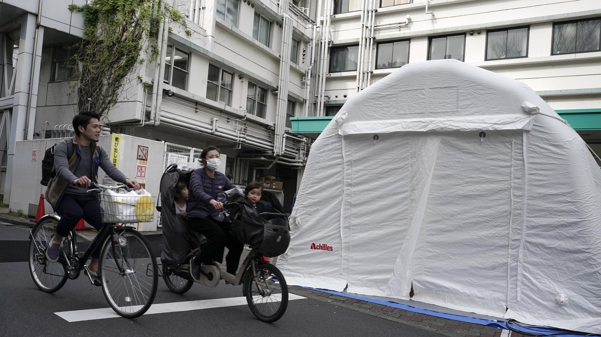 epa08374699 A family cycles past tents for COVID-19 testing outside Kawakita General Hospital in Tokyo, Japan, 21 April 2020. Japan has recently witnessed a sharp rise in infections. Prime Minister Shinzo Abe declared on 16 April 2020 a nationwide state of emergency. According to media reports, a new wave of COVID-19 infections is threatening the country’s healthcare system, with several hospitals forced to turn away sick people.  EPA/KIMIMASA MAYAMA