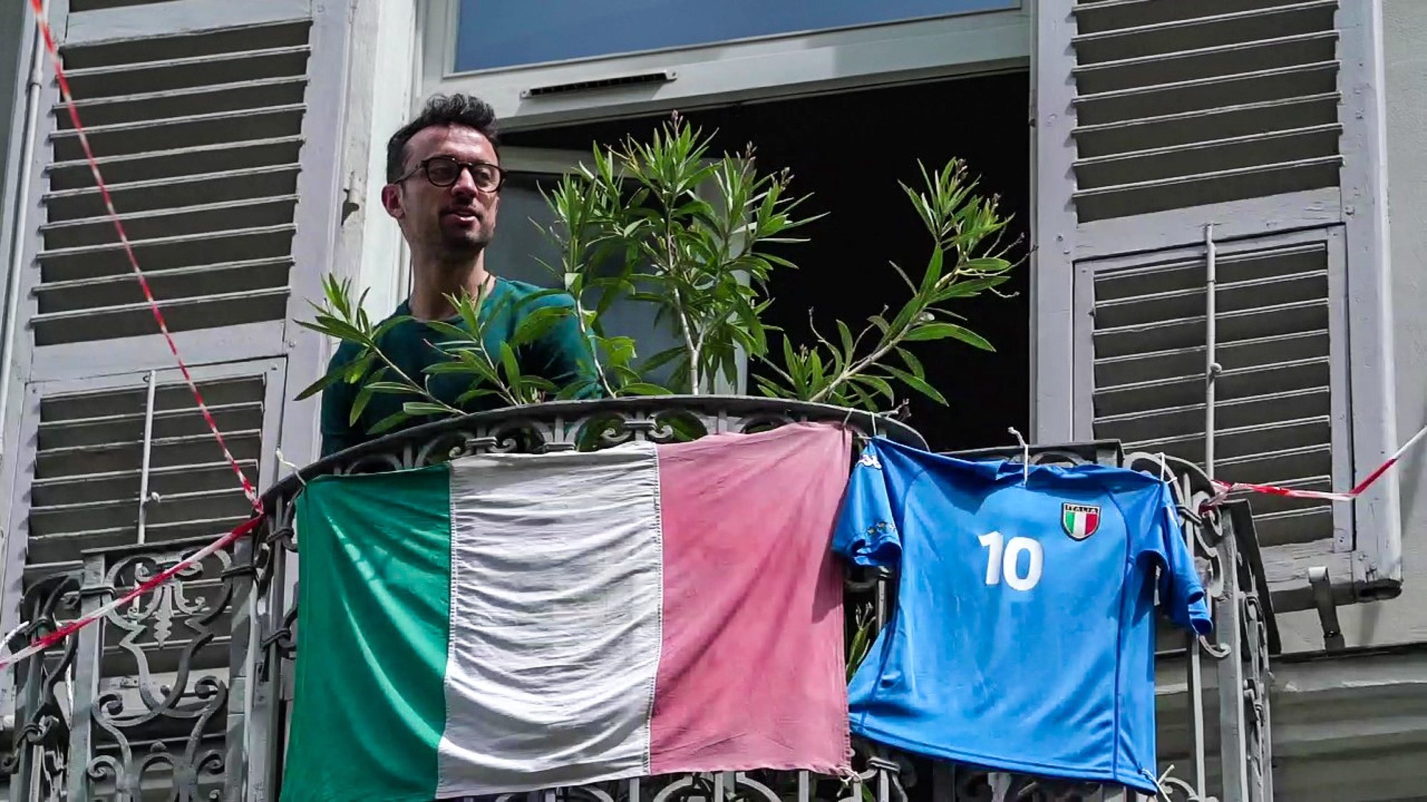epa08395770 A man on the balcony displays the Italian flag and the jersey of the national football team amid the ongoing pandemic of the COVID-19 disease caused by the SARS-CoV-2 coronavirus in Turin, Italy,  01 May 2020.  EPA/TINO ROMANO