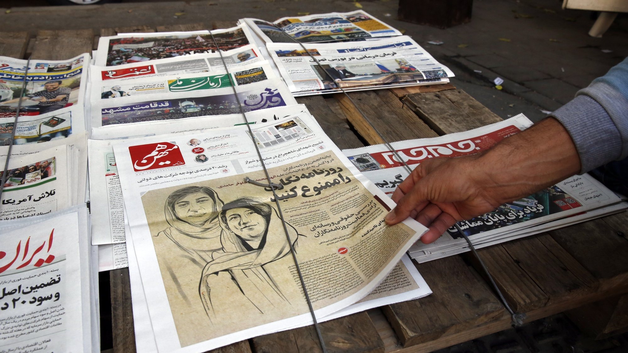 epa10274828 An Iranian man picks up a copy of Iranian daily newspaper Hammihan with a drawing featuring two Iranian female journalists Niloufar Hamedi and Elaheh Mohammadi with a title &#039;Ban the journalism&#039; referring to the statement by the Tehran journalists&#039; association against the prisoning journalists over covering protests in Iran, on display in a kiosk in Tehran, Iran, 30 October 2022. Niloufar Hamedi and Elaheh Mohammadi who are journalist for Iranian local daily newspaper were first two journalists who covered and published death of Mahsa Amini, and later were arrested and now are in prison. After Iranian government accused the two female journalists to conspiracy against the country, Tehran journalists&#039; association published a statement as saying that &#039;journalism is not a crime&#039;. Some Iranian journalists and photojournalists have been arrested and are in prison since the anti-government protests started in the country.  EPA/ABEDIN TAHERKENAREH