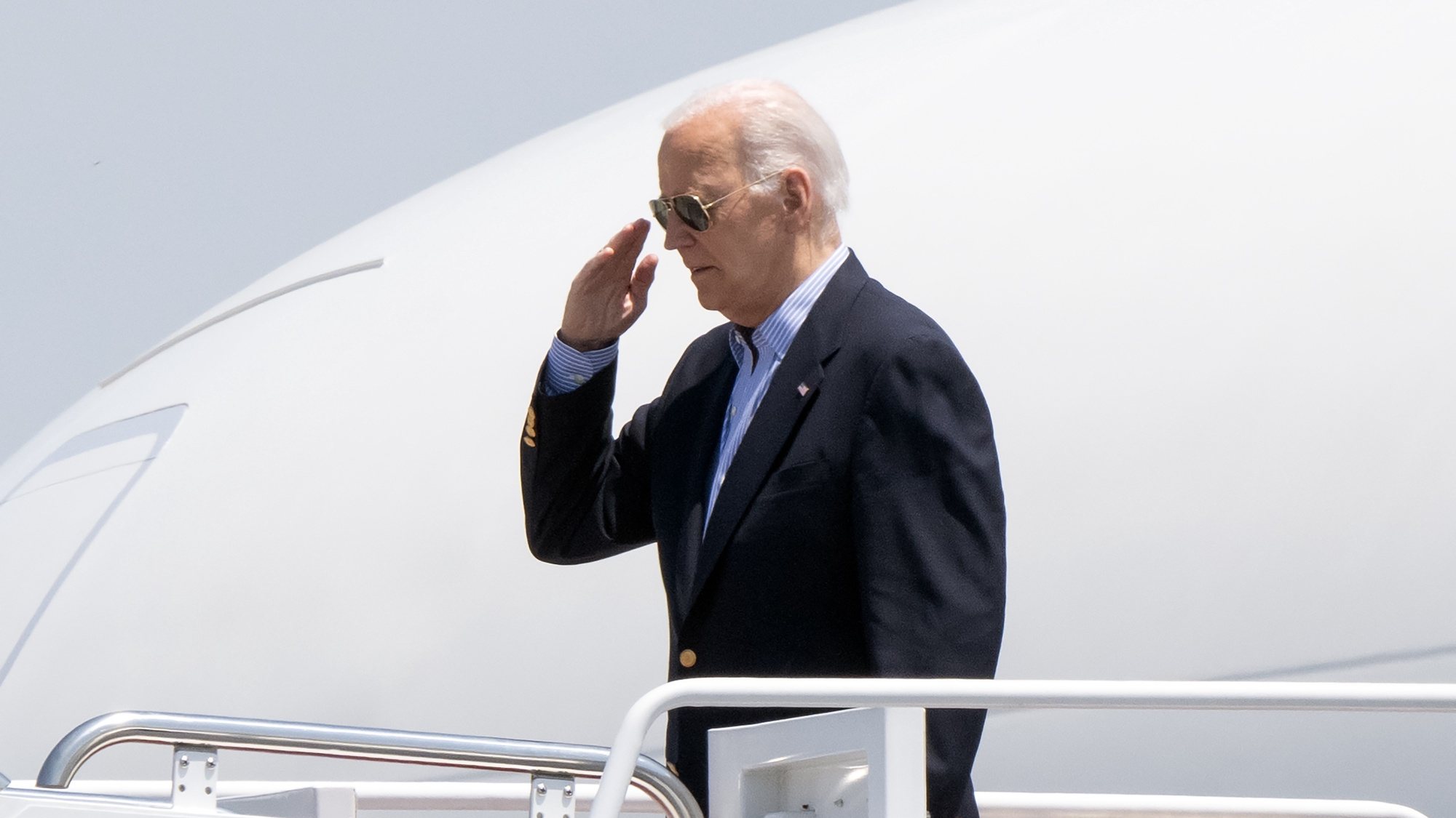 epa11459942 United States President Joe Biden salutes as he boards Air Force One at Joint Base Andrews, to travel to Madison, Wisconsin in Camp Springs, Maryland, USA, 05 July 2024.  The President will participate in a campaign event in Madison before proceeding to Wilmington, Delaware for the weekend.  EPA/RON SACHS / POOL