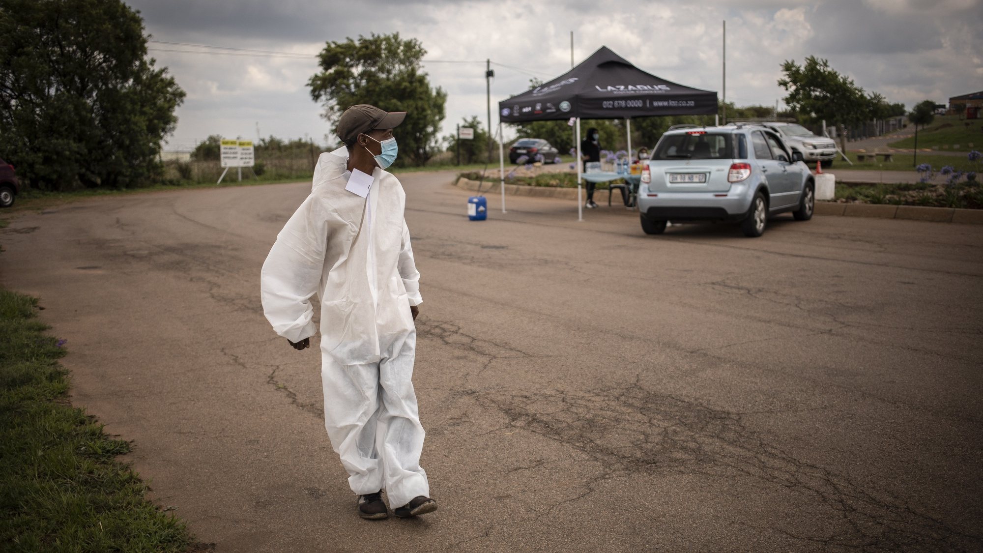 epa09642824 A volunteer wears personal protective equipment (PPE) at a Covid-19 drive-through vaccination facility at the Zwartkops Raceway in Pretoria, South Africa, 15 December 2021. The facility opened in an effort to increase vaccinations prior to the start of the annual end of year holidays, amid Omicron variant fears.  EPA/Kim Ludbrook