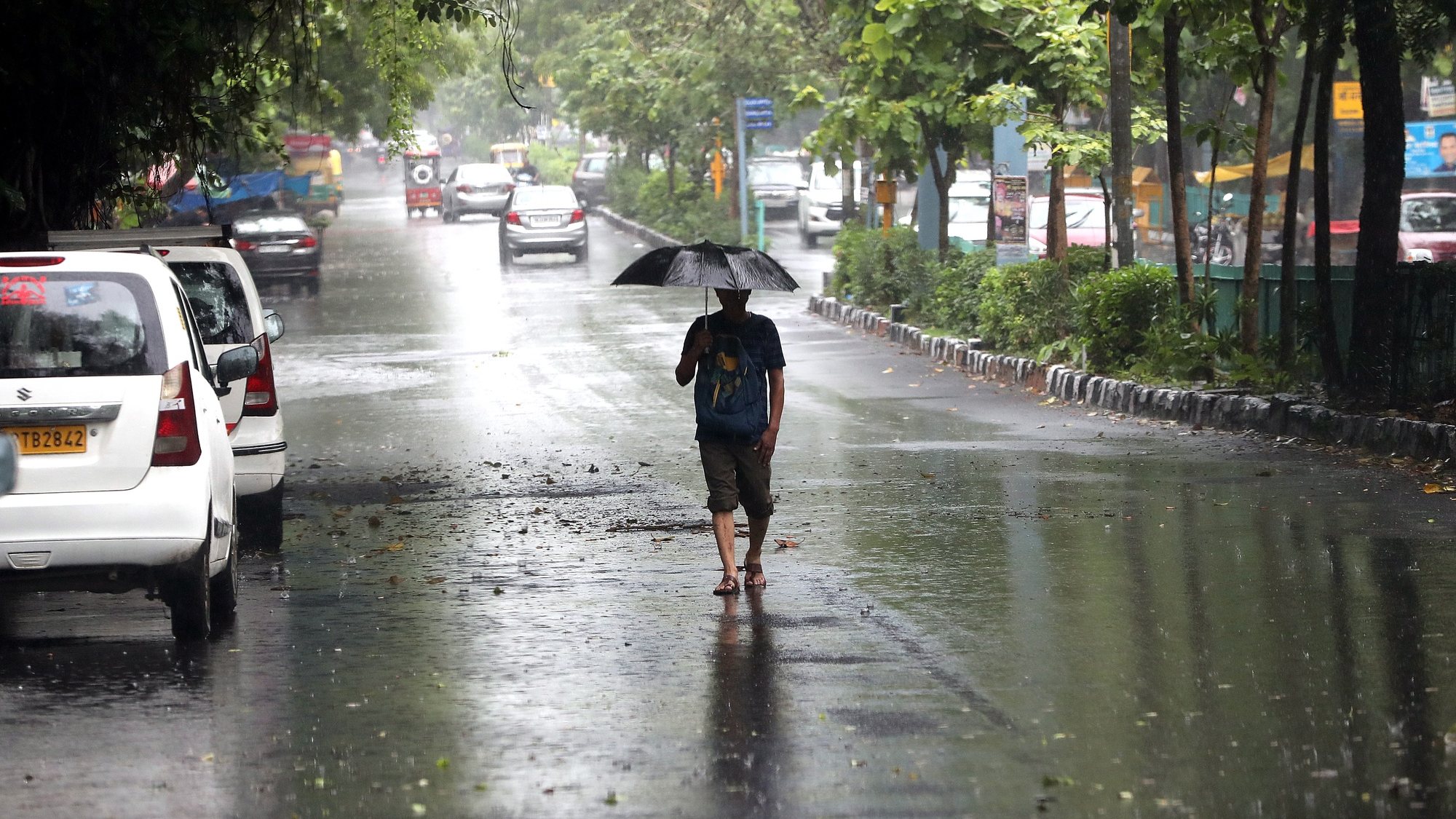 epa10737441 A man walks with his umbrella amid the rain in New Delhi, India, 10 July 2023. The water level at the old railway bridge reached 203.18 metres and the warning level is 204.5 metres. The India Meteorological Department said that Delhi received 153 mm of rain in 24 hours ending at 8:30 a.m. on 09 July, the most in a July day since 1982.  EPA/HARISH TYAGI