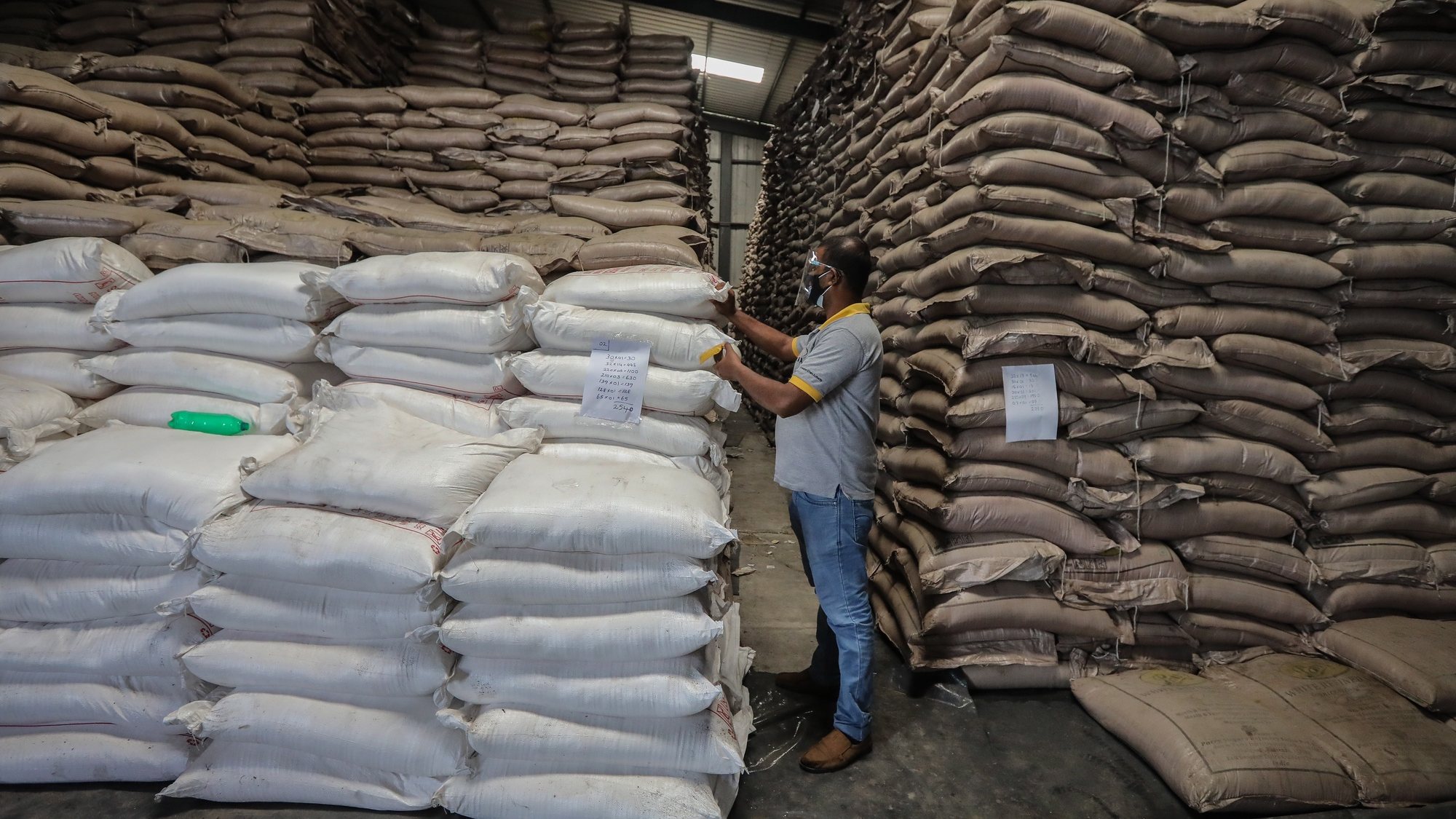 epa09469491 An official from Sri Lankaâ€™s Consumer Affairs Authority (CAA) inspects a large stock of sugar at a warehouse in Colombo, Sri Lanka, 13 September 2021 (issued 15 September 2021). With the onset of the Covid-19 pandemic and economic crisis, there was a shortage of essential food items emerged throughout the country creating ques at some retail shops. The Sri Lankan government imposed emergency regulations under the Public Security Ordinance on 30 August to curtail skyrocketing of essential food items by hoarding and artificial shortages. Meanwhile, Islandâ€™s Consumer Affairs Authority launched raids on black market retailers and acquired some food stocks by traders and food importers.  EPA/CHAMILA KARUNARATHNE