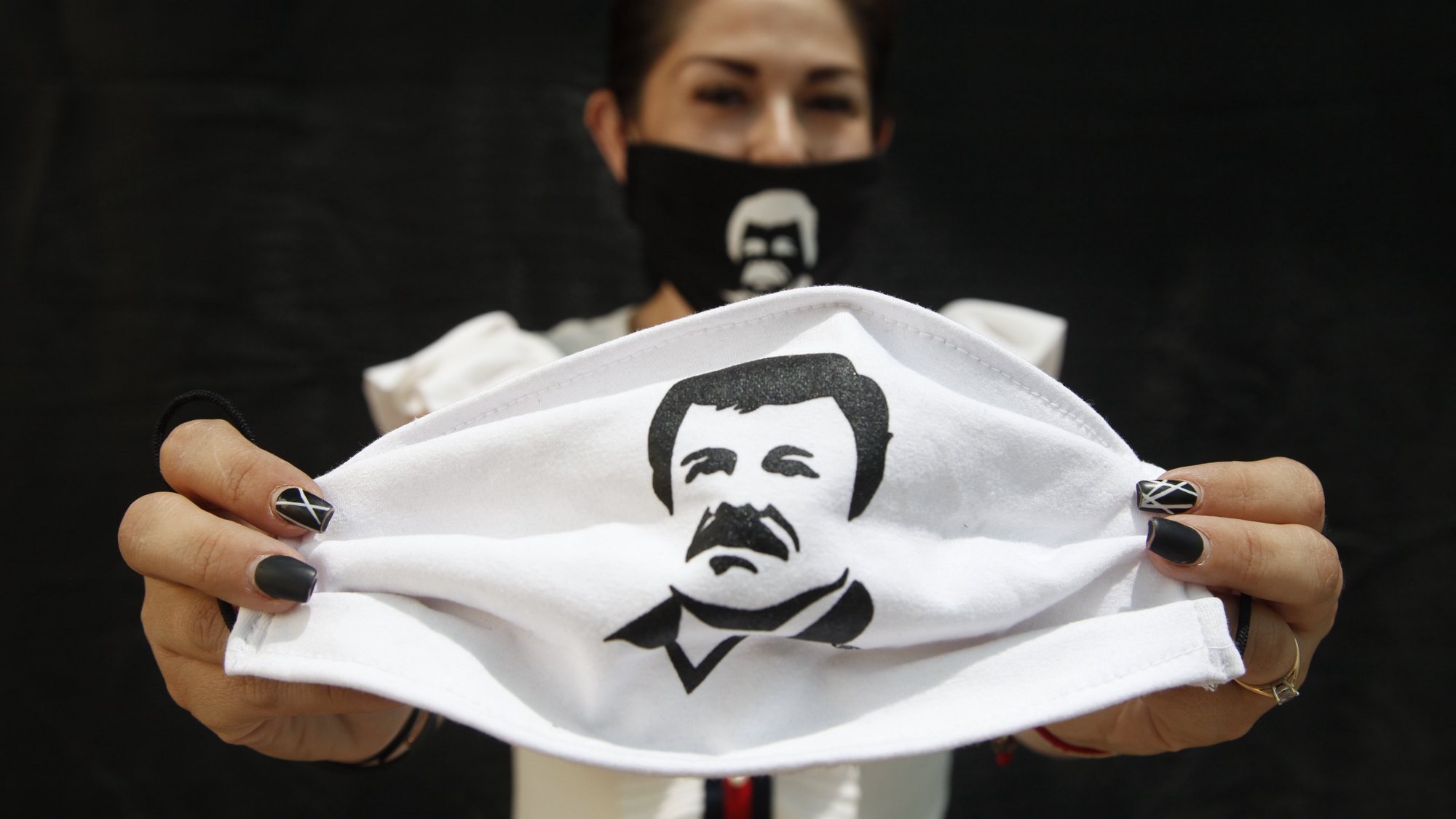 epa08367814 A person holds a face mask, which depicts famed drug lord Joaquin &#039;El Chapo&#039; Guzmanto, in Guadalajara, Jalisco, Mexico, 16 April 2020. According to media reports, Alejandrina Guzman, daughter of Joaquin &#039;El Chapo&#039; Guzman, has helped in the distribution of aid and supplies, labelled with the name and image of her father, to members of the public during the outbreak of coronavirus in Mexico.  EPA/Francisco Guasco