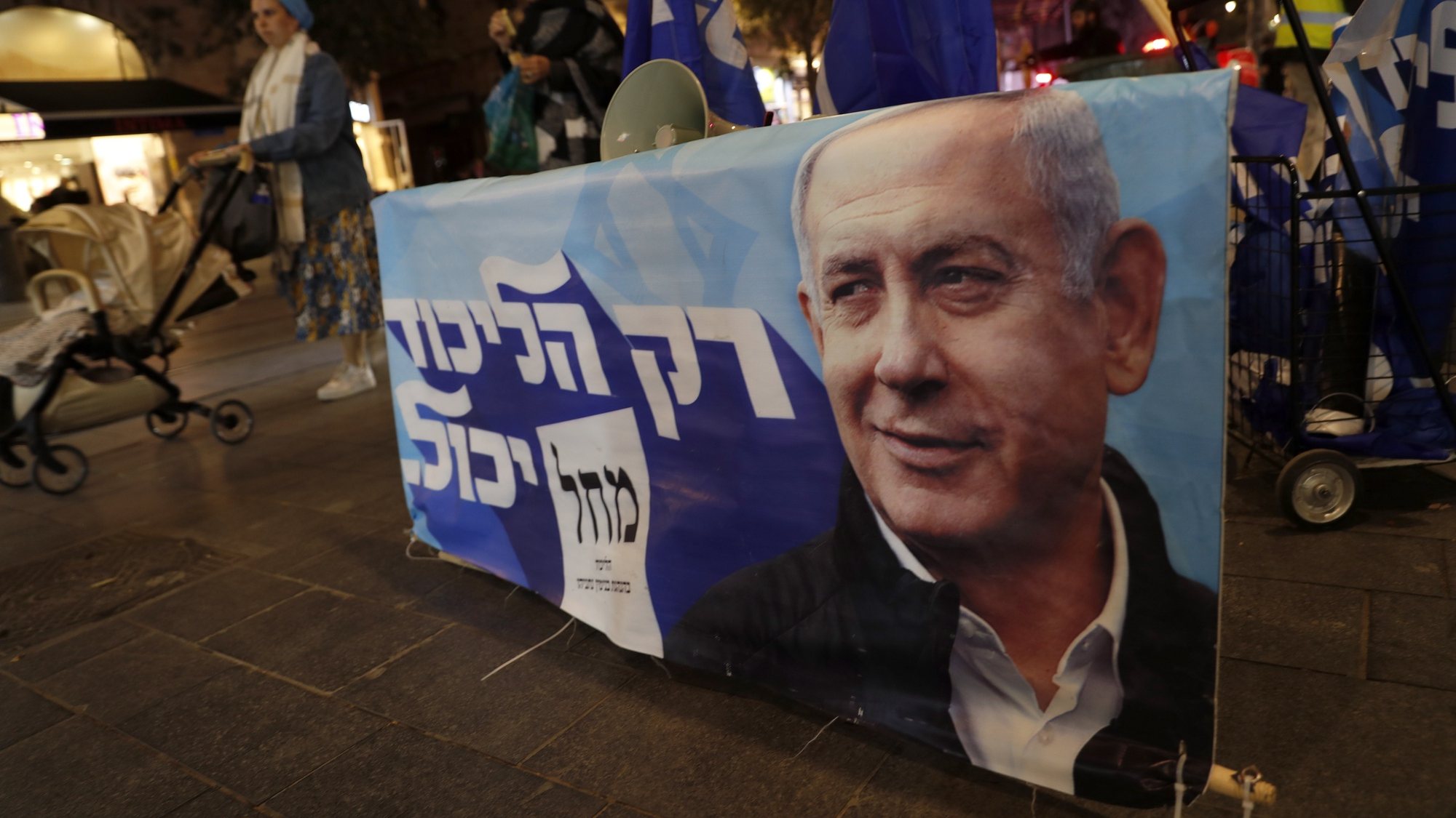 epa10277328 A supporter of the former Israeli Prime Minister and leader of the Likud party Benjamin Netanyahu display his Likud party campaign poster ahead of the General elections in center Jerusalem, 31 October 2022. General elections are scheduled for 01 November 2022.  EPA/ATEF SAFADI