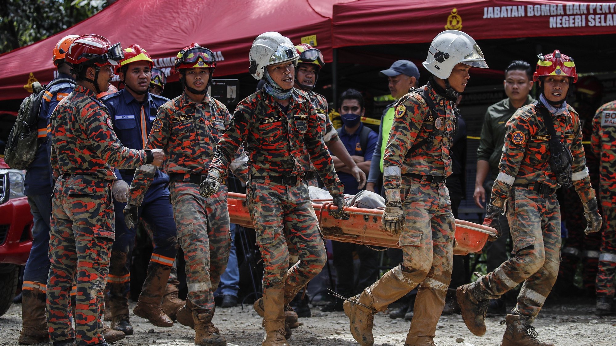 epa10368106 Malaysia Fire and Rescue Department officers carry a victim&#039;s body after a landslide hit the campsite in Batang Kali, state of Selangor, Malaysia, 16 December 2022. A landslide at a tourist campground in Malaysia left 16 people dead. According to the authorities, others were feared buried at the site at an organic farm outside the capital of Kuala Lumpur.  EPA/FAZRY ISMAIL
