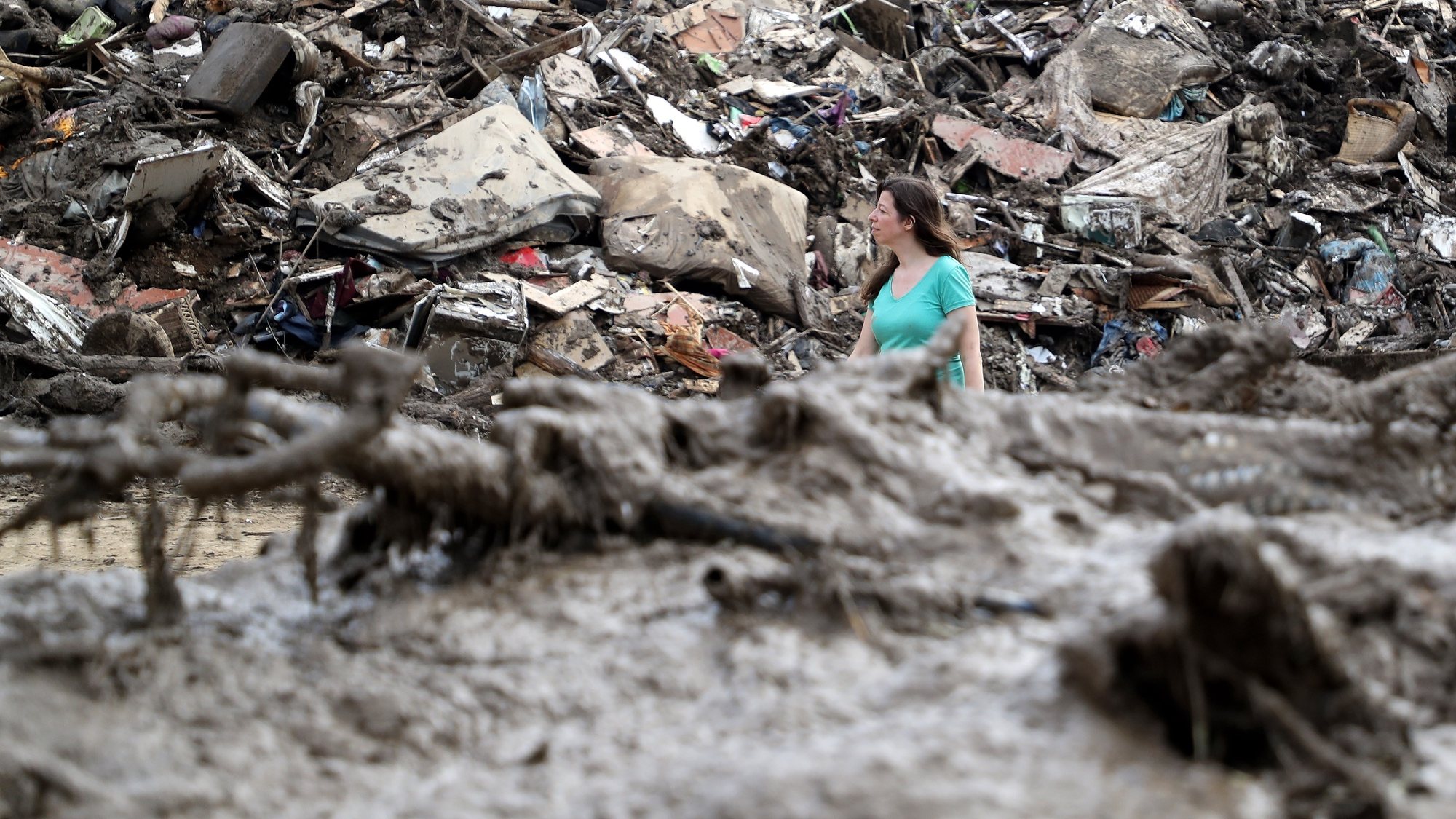 epa09353768 A person walks between the piled up rubbish after the flooding of the Ahr River, in Altenahr, Germany, 19 July 2021. Large parts of western Germany and central Europe were hit by flash floods in the night of 14 to 15 July, following days of continuous rain that destroyed buildings and swept away cars. The total number of victims in the flood disaster in western Germany rises to at least 164, with many hundreds still missing.  EPA/FRIEDEMANN VOGEL