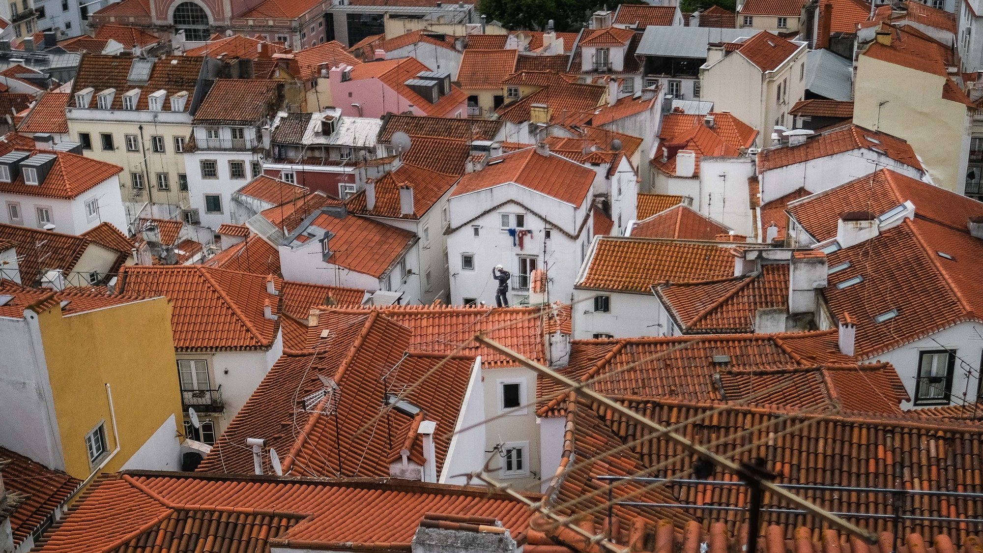 Um trabalhador nos telhados de Alfama, em Lisboa, 18 de junho de 2021. O Governo decidiu proibir as deslocações de e para a Área Metropolitana de Lisboa (AML) no fim de semana devido à subida dos casos de covid-19 neste território. MÁRIO CRUZ/LUSA