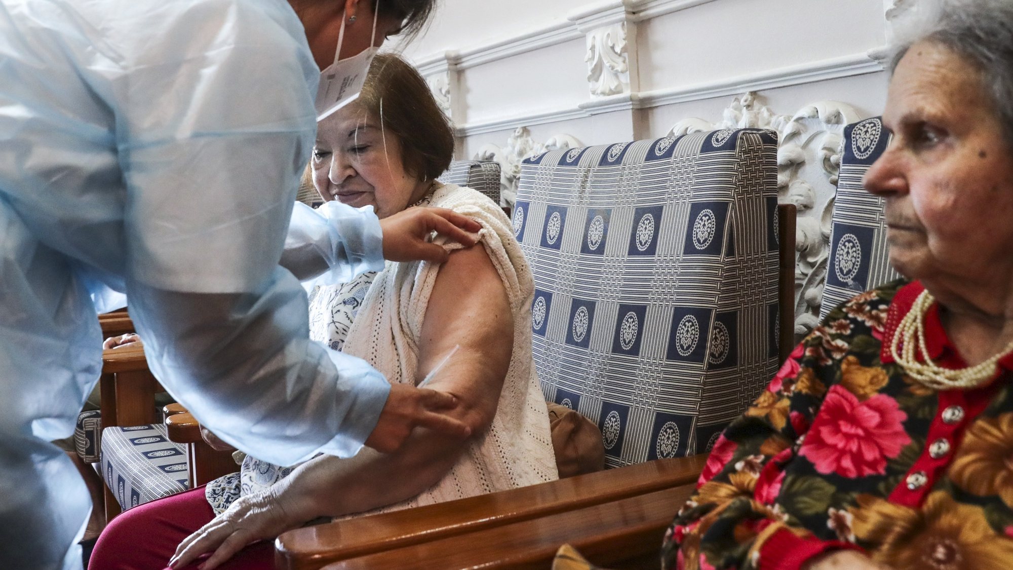 Uma utente de um lar de terceira idade é vacinada por uma enfermeira com a quinta dose da vacina contra a covid-19, em Lisboa, 19 de maio de 2022. TIAGO PETINGA/LUSA