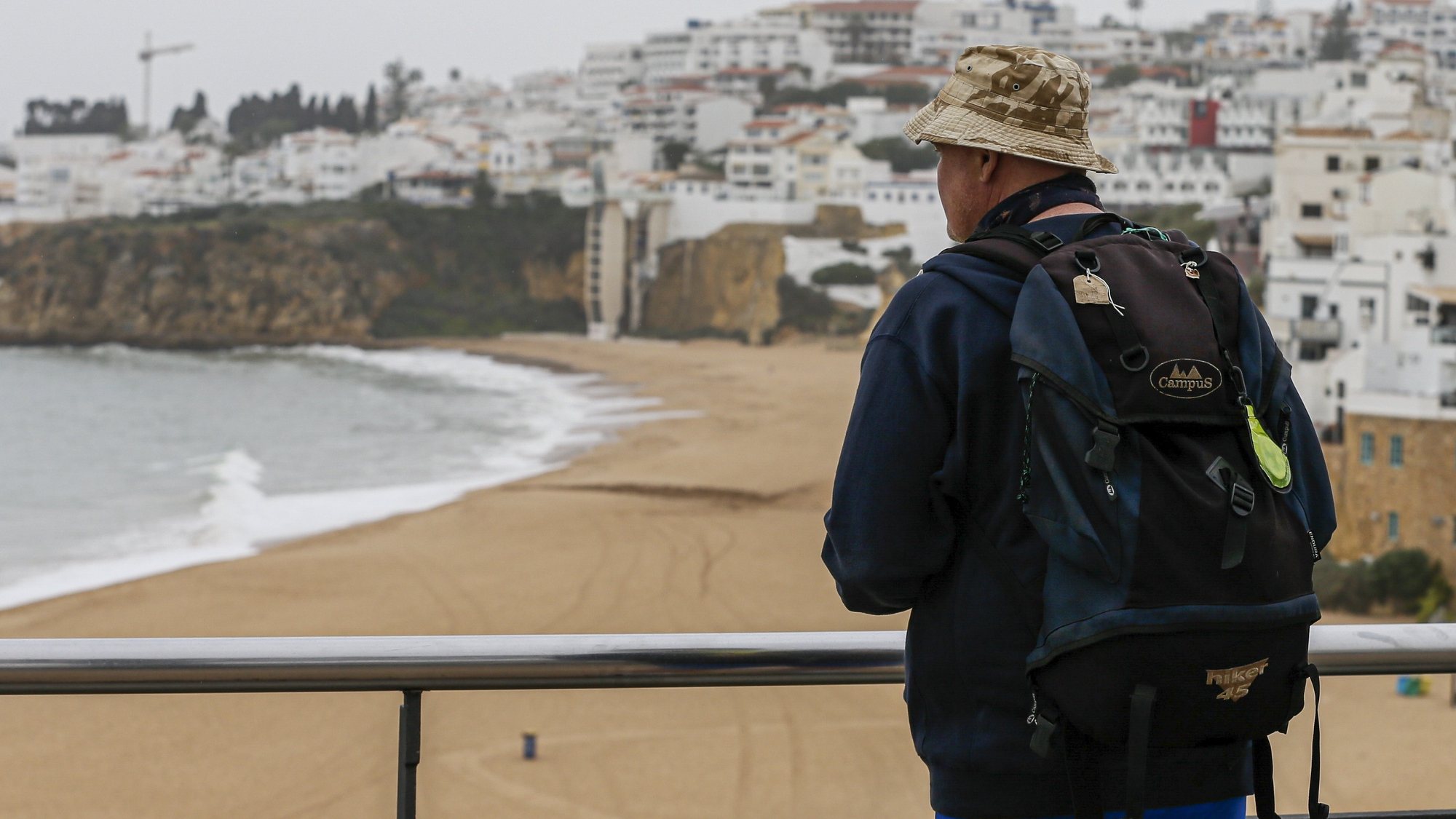 epa08307447 A tourist looks at the beach of Albufeira, Algarve, southern Portugal, 19 March 2020. Countries around the world are taking increased measures to stem the widespread of the SARS-CoV-2 coronavirus which causes the Covid-19 disease. Portugal is in a state of emergency since midnight 19 March 2020.  EPA/LUIS FORRA