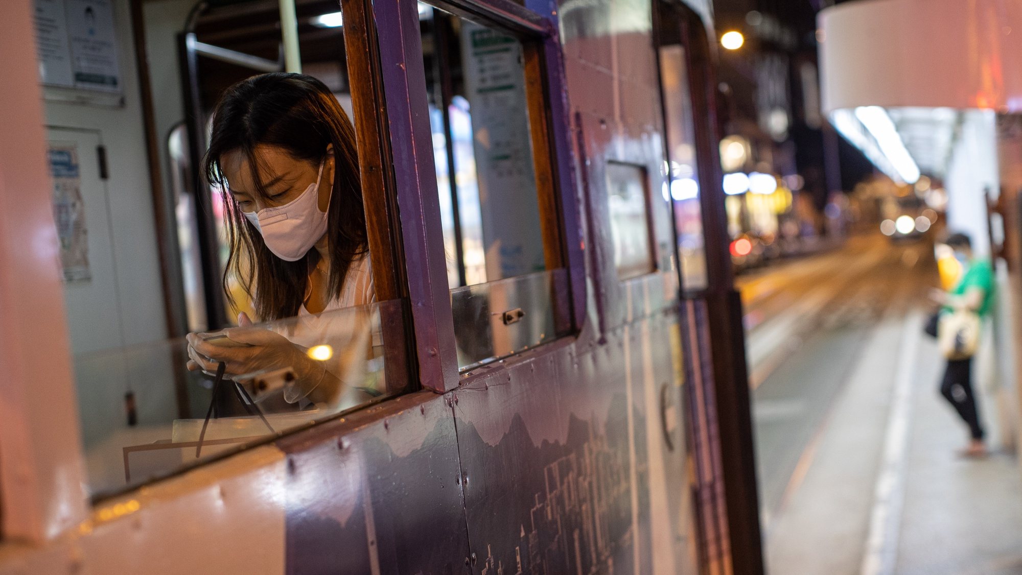epa08570524 A woman wears a face mask and rubber gloves while riding the tram in Hong Kong, China, 28 July 2020. Hong Kong reported new coronavirus COVID-19 infections in triple digits for the seventh straight day.  EPA/JEROME FAVRE