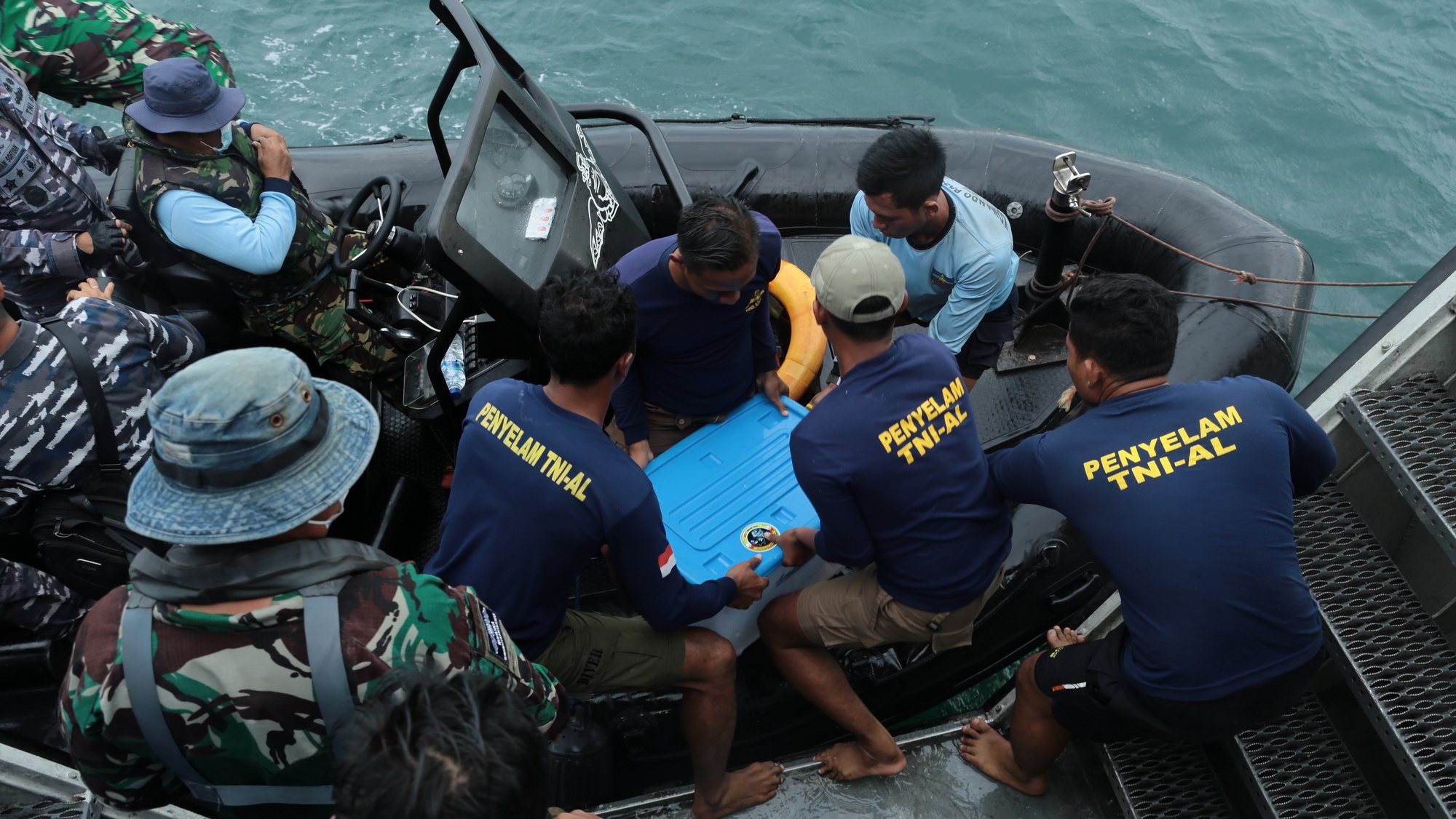 epa08932563 Indonesian Navy personnel move a plastic container carrying a black box of the crashed Sriwijaya Air plane, recovered from the wreckage, onto a sea reader boat, in waters off Jakarta, Indonesia, 12 January 2021. Indonesia&#039;s navy divers recovered the flight data recorder (FDR) of the Sriwijaya Air Boeing 737-500 plane that crashed into the waters off the coast of Jakarta with 62 people on board.  EPA/STR