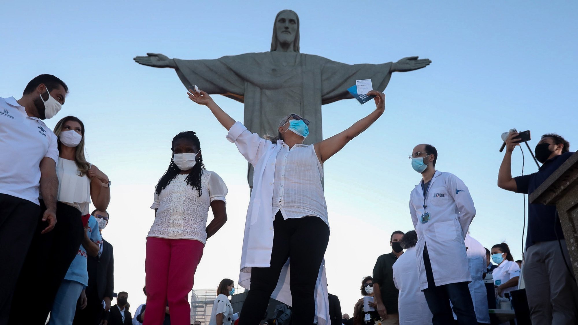 epaselect epa08947413 Dulcineia da Silva (L), 59, a nurse from the public health network and Terezinha da Conceicao (R), 80, who lives in a shelter for a population in a situation of social vulnerability, are vaccinated in a symbolic act at the feet of the emblematic statue of Christ the Redeemer on the Corcovado hill, in Rio de Janeiro, Brazil, 18 January 2021. Brazil one of the countries most affected by COVID-19 in the world, exceeded the 210,000 victims mark precisely on the day the vaccination campaign began throughout the country.  EPA/FABIO MOTTA