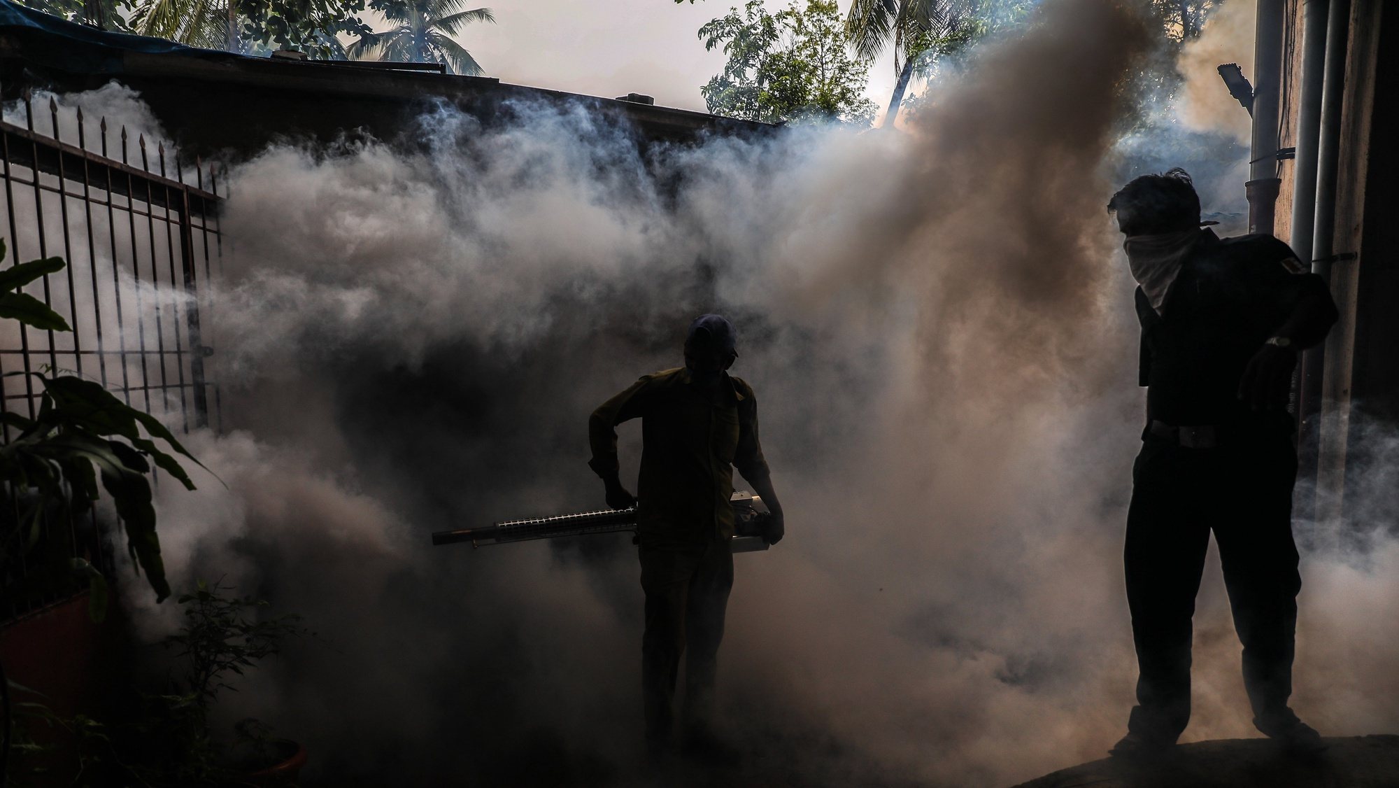 epa08570594 A municipal worker wearing a face mask uses an anti-malaria fumigation spray machine at a residential area in Mumbai, India, 28 July, 2020. The measure is regularly taken by the municipal corporation to try to avoid any kind of diseases caused by mosquitoes. The workers, reportedly, fumigate in all areas of the city, from slum to high rise residential buildings, from shops to sewage canals, ponds and puddles in the streets.  EPA/DIVYAKANT SOLANKI