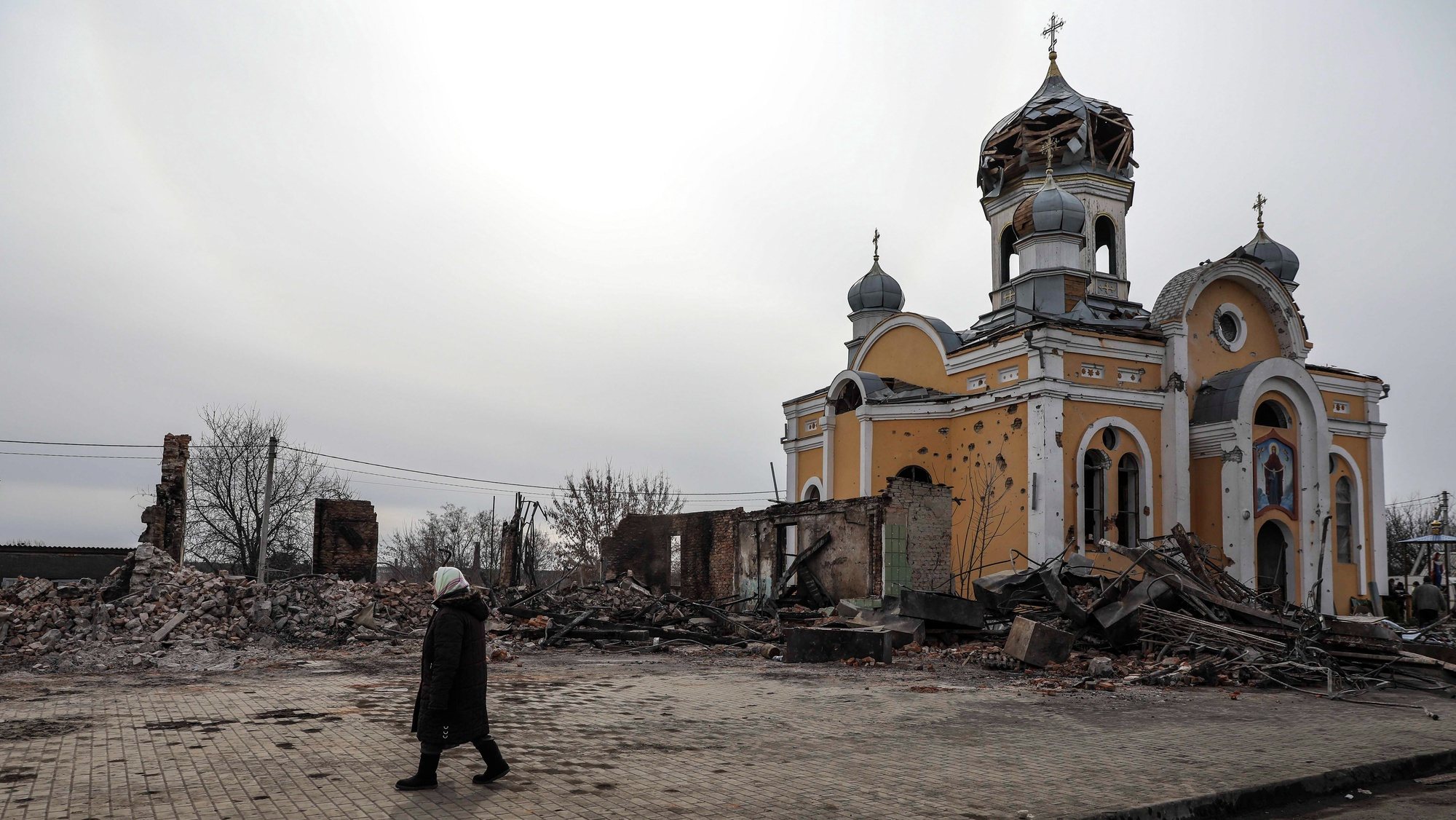 Uma mulher perto da Igreja Ortodoxa destruída em bombardeamentos russos em Malyn, na Ucrânia