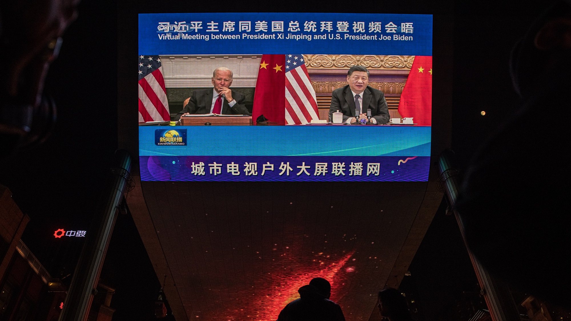 epa09585287 People stand in front of a big screen showing US President Joe Biden (L) and Chinese President Xi Jinping attending their virtual summit, during the evening news program, in Beijing, China, 16 November 2021. US President Joe Biden and Chinese President Xi Jinping had their first face-to-face virtual summit amid the political and economic tensions between the two countries.  EPA-EFE/ROMAN PILIPEY