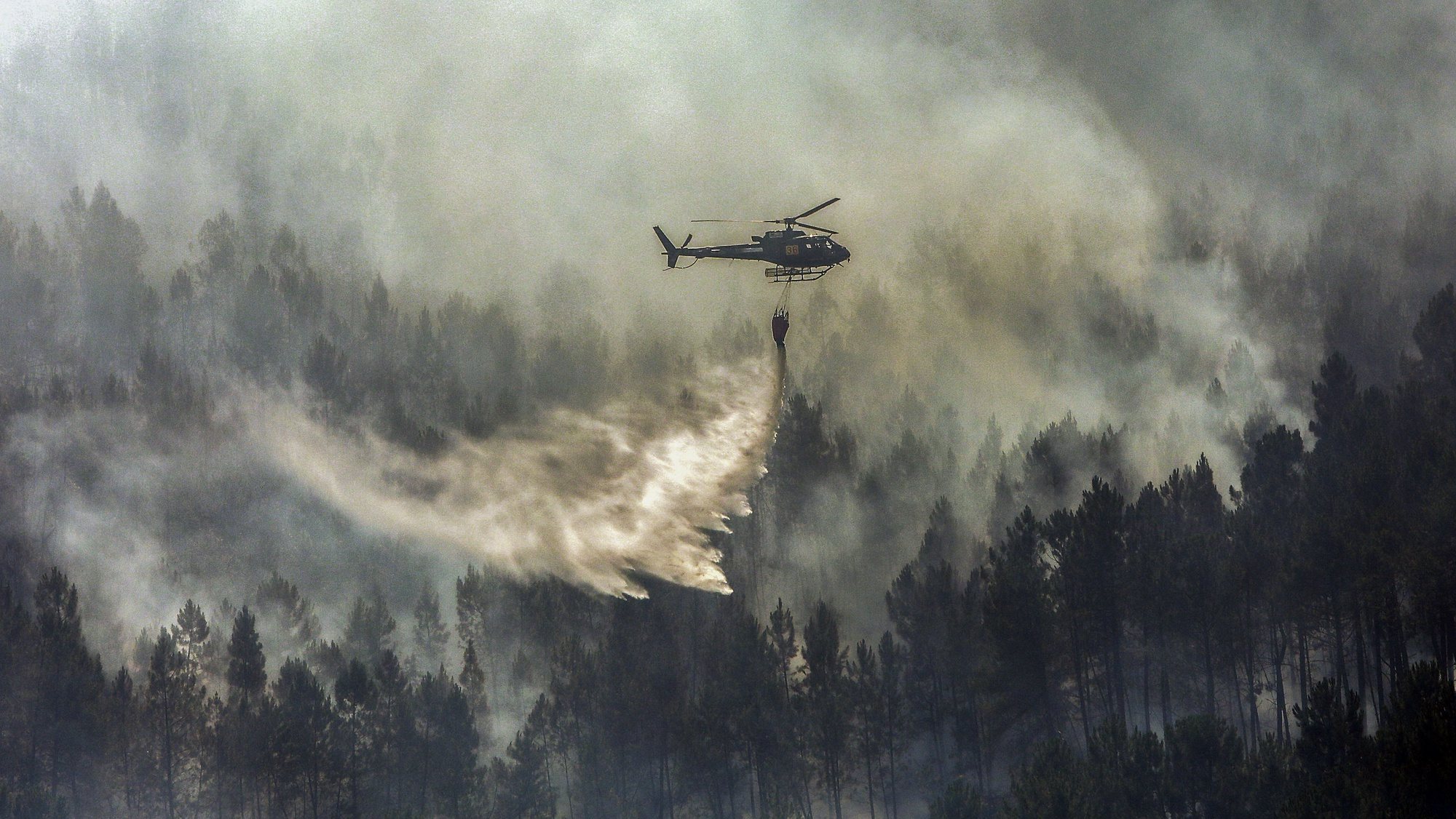 Um helicóptero combate as chamas durante um incêndio no vale glaciar de Beijames, Covilhã, 9 de agosto de 2022. Este incêndio que deflagrou no sábado na localidade de Garrocho, no concelho da Covilhã (Castelo Branco), continua ativo e está a ser combatido por mais de 580 operacionais. MIGUEL PEREIRA DA SILVA/LUSA