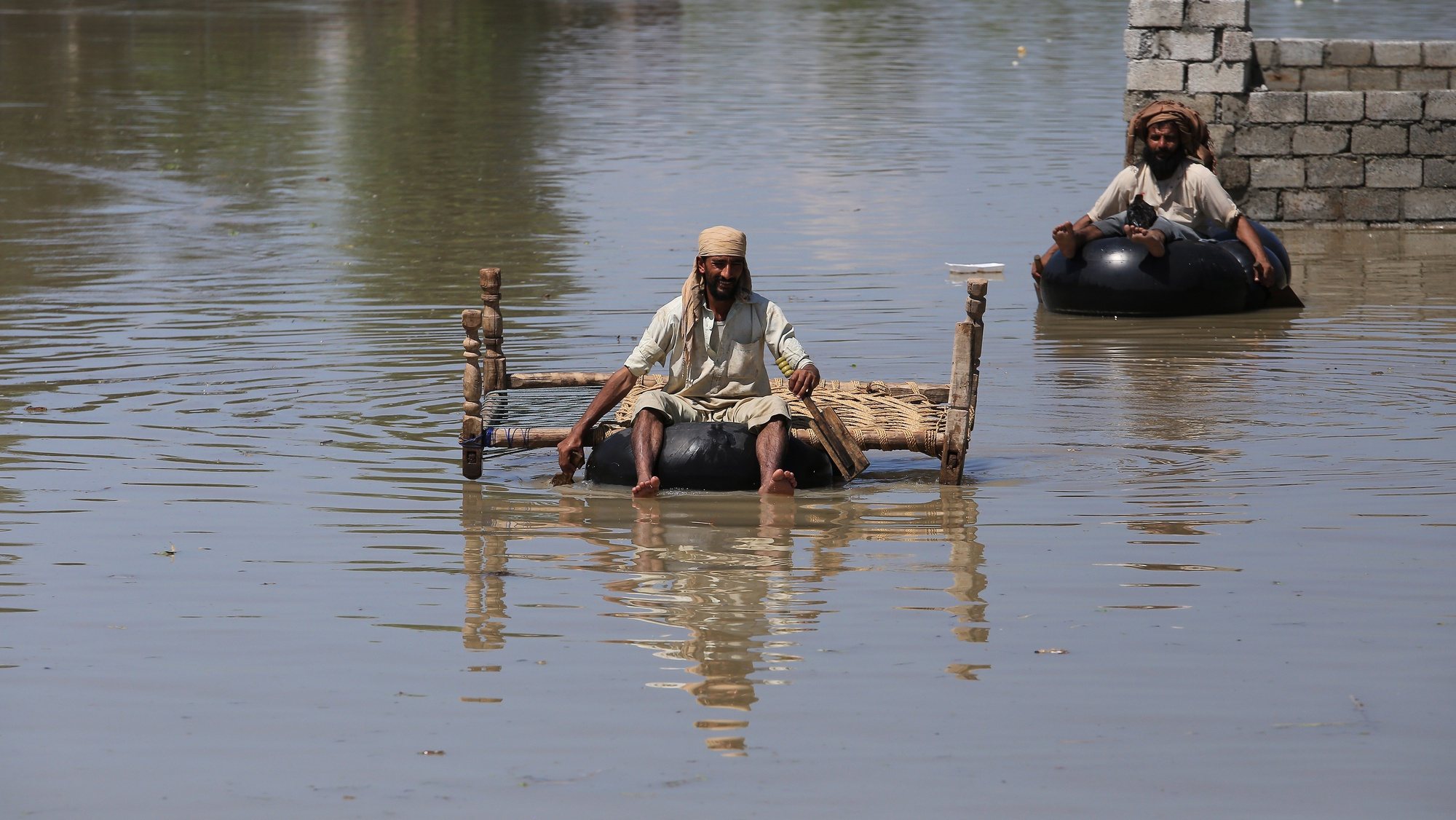 epa10143298 A man rides an improvised floating device in a flooded area following heavy rains in Charsadda District, Khyber Pakhtunkhwa province, Pakistan, 28 August 2022. According to the National Disaster Management Authority (NDMA) on 27 August, flash floods triggered by heavy monsoon rains have killed over 1,000 people across Pakistan since mid-June 2022. More than 33 million people have been affected by floods, the country&#039;s climate change minister said.  EPA/ARSHAD ARBAB