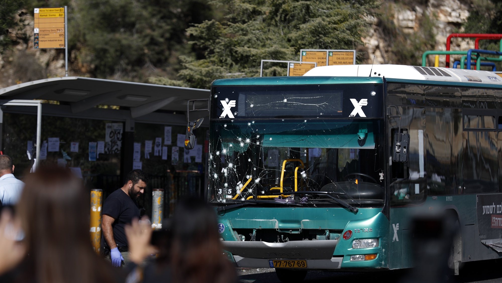 epa10321785 Israeli security forces stand near a damaged bus at the site of explosion at a bus stop at Ramot Junction, near Jerusalem, Israel, 23 November 2022. According to Israeli police, at least 14 people were injured in two explosions at two bus stops at the Givat Shaul Junction and near Ramot Junction in Jerusalem. Israel Police forces rushed to both scenes, collecting evidence and testimonials, and taking action to locate possible suspects.  EPA/ATEF SAFADI