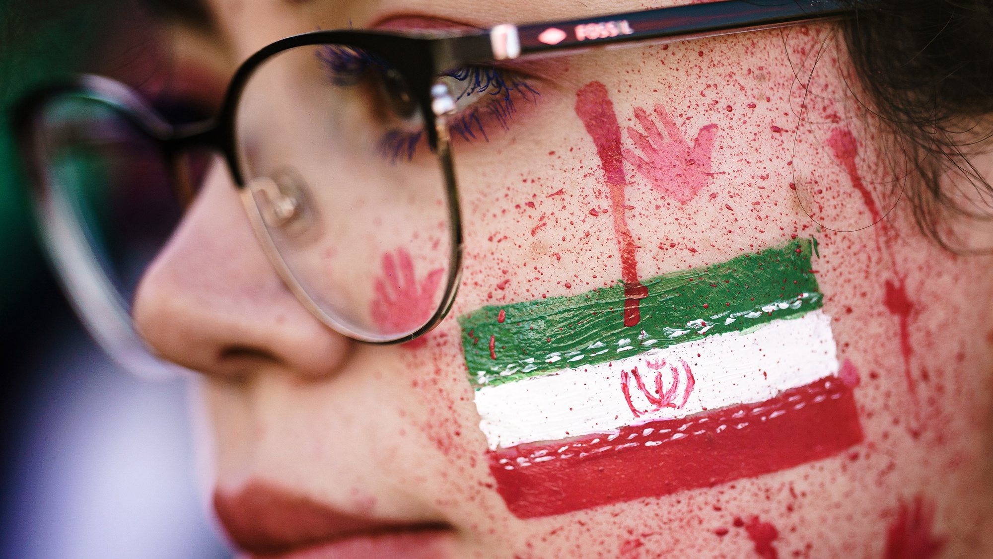 epa10364983 epa10229335 A protester shows red paint in her face, resembling blood splatters and bloody handprints next to the national Iranian emblem, during a rally in solidarity with Iranian protests following the death of Mahsa Amini, in Berlin, Germany, 07 October 2022. Amini, a 22-year-old Iranian woman, was arrested in Tehran on 13 September by the police unit responsible for enforcing Iran&#039;s strict dress code for women. She fell into a coma while in police custody and was declared dead on 16 September.  EPA/CLEMENS BILAN  EPA-EFE/CLEMENS BILAN