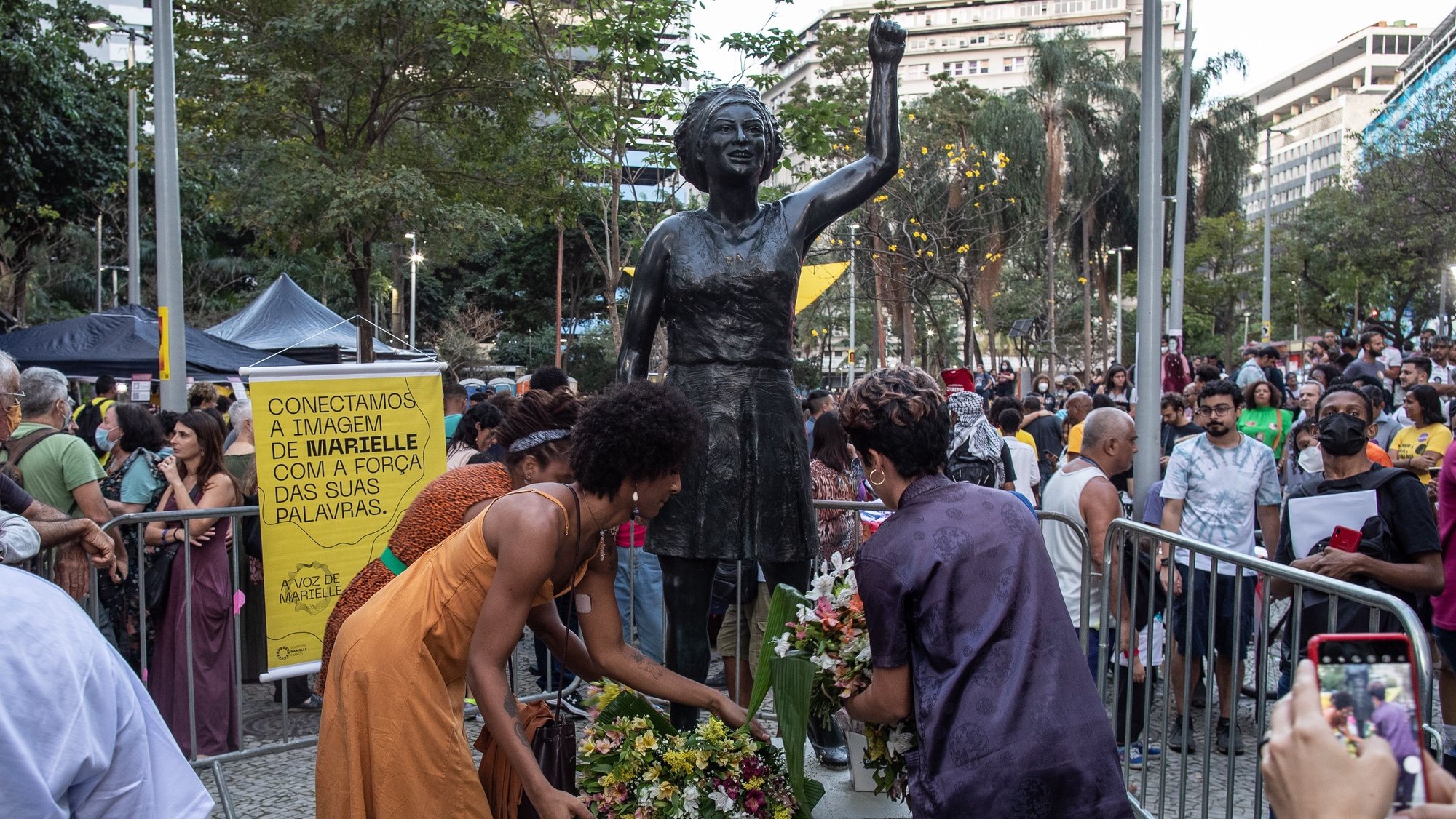 epa10094697 People gather around the life-size statue of former councilwoman Marielle Franco during its inauguration in downtown Rio de Janeiro, Brazil, 27 July 2022. The Brazilian councilor, left-wing activist and human rights defender Marielle Franco, murdered in 2018 in a case still unpunished, can be remembered in the same place where she became famous as a politician thanks to the inauguration of a bronze statue in her tribute. The life-size statue (1.75 meters), sculpted by the artist Edgar Duvidier, was unveiled at the Buraco do Lume, an emblematic place in downtown Rio de Janeiro where the Rio de Janeiro councilor went every Friday to talk with her constituents.  EPA/Andre Coelho